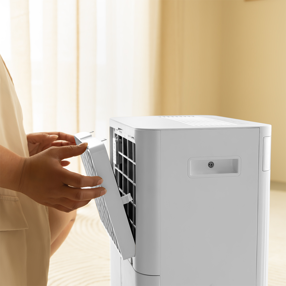 Person removing a white filter from a white air conditioner unit.