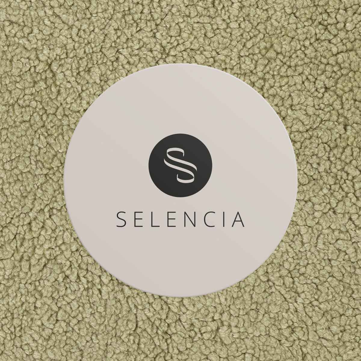 A white circle with the Selencia logo on a light green fluffy background.
