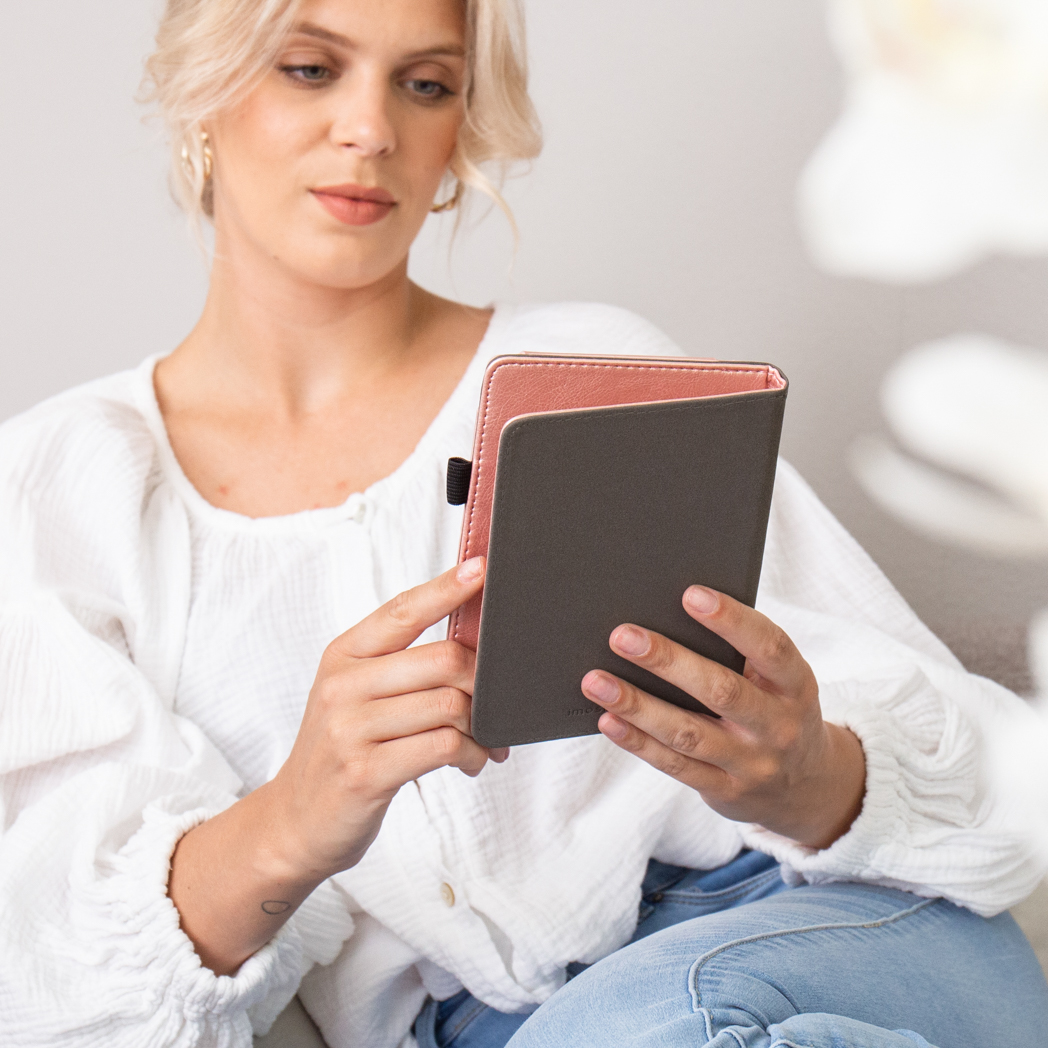 Une femme tient un carnet gris et rose dans ses mains.