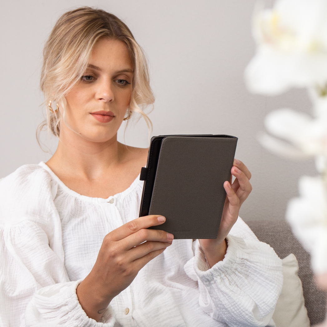 Een blonde vrouw zit met een donkere e-reader in haar handen.