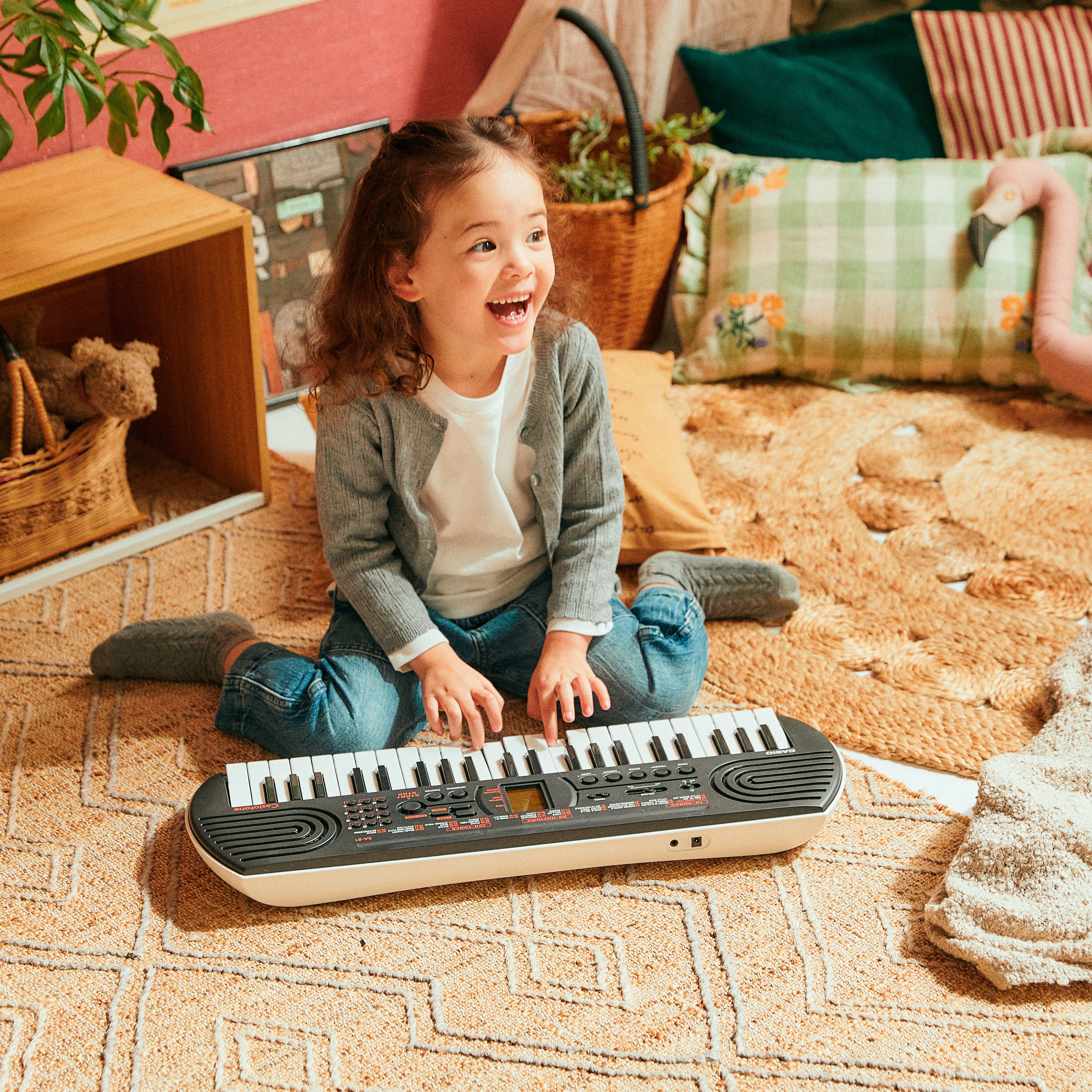 Ein kleines Mädchen spielt auf einem Keyboard im Wohnzimmer.