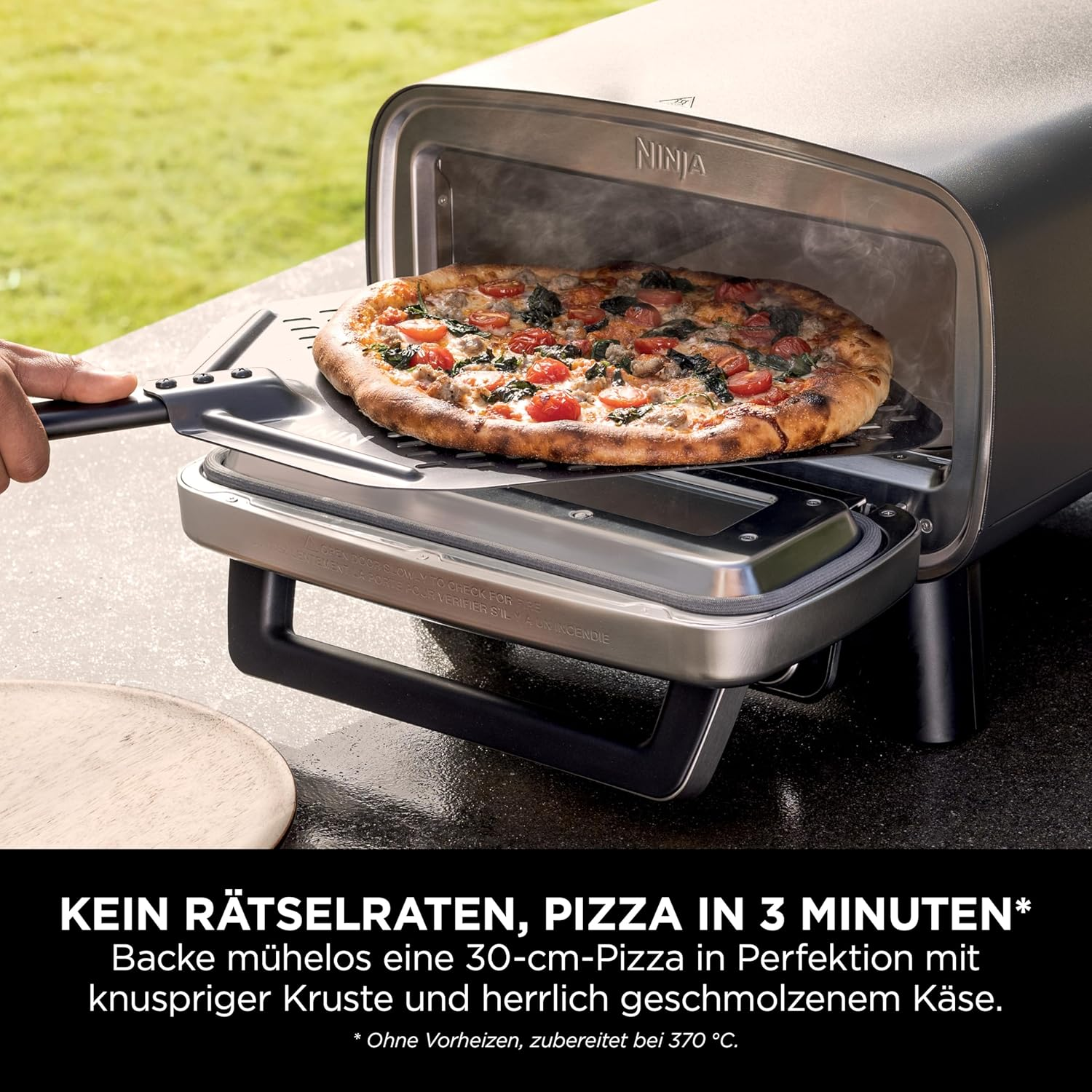A pizza is being removed from a Ninja oven with a pizza peel.
