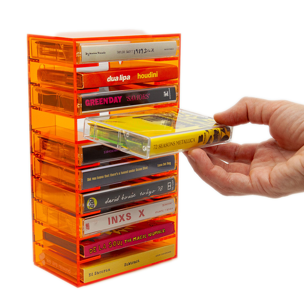 Porte-cassettes orange avec cassettes, une main en sort une.