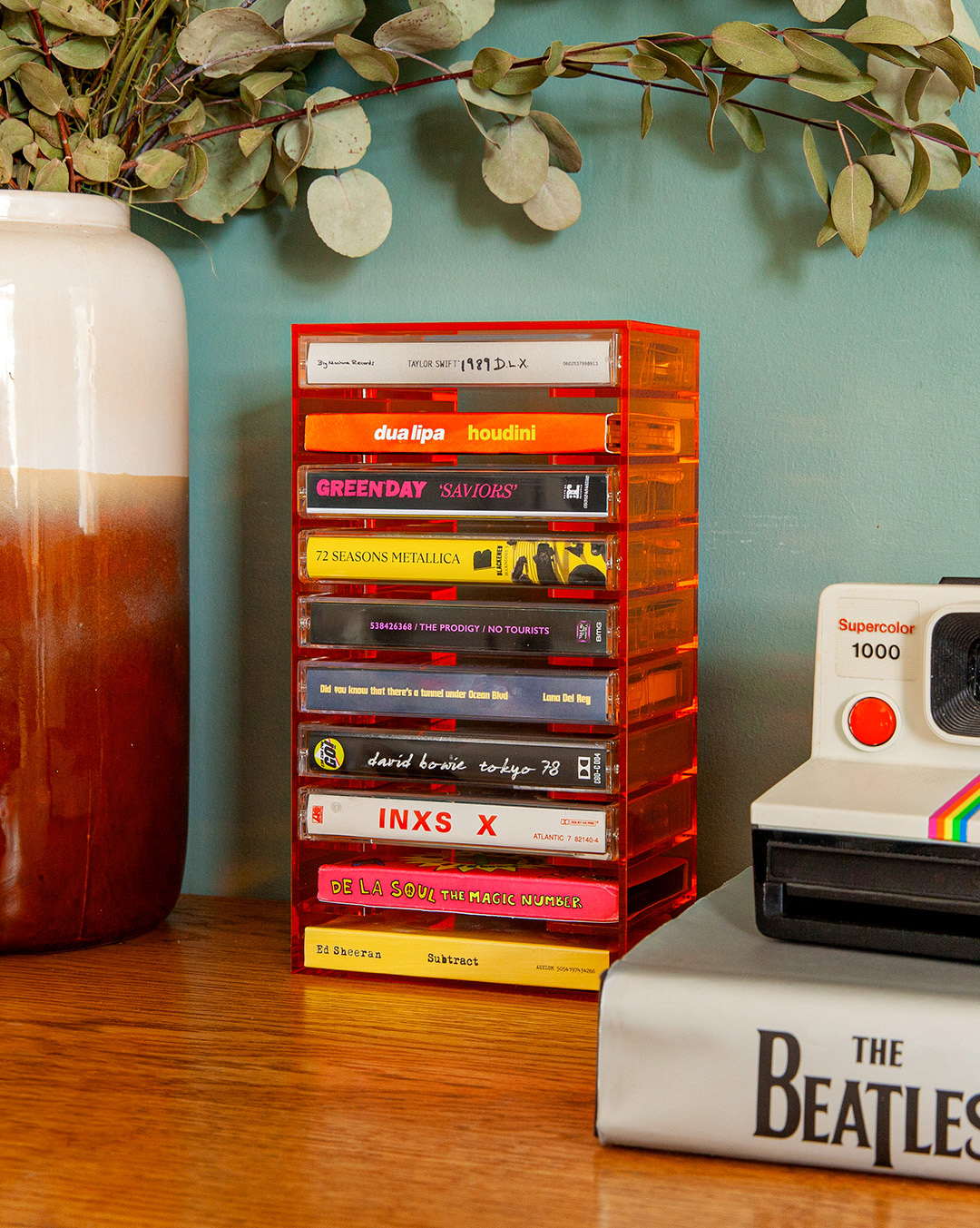 Un porte-cassettes orange avec des albums de Taylor Swift, Dua Lipa, Green Day, Metallica, Lana Del Rey, David Bowie, INXS, De La Soul, Ed Sheeran.