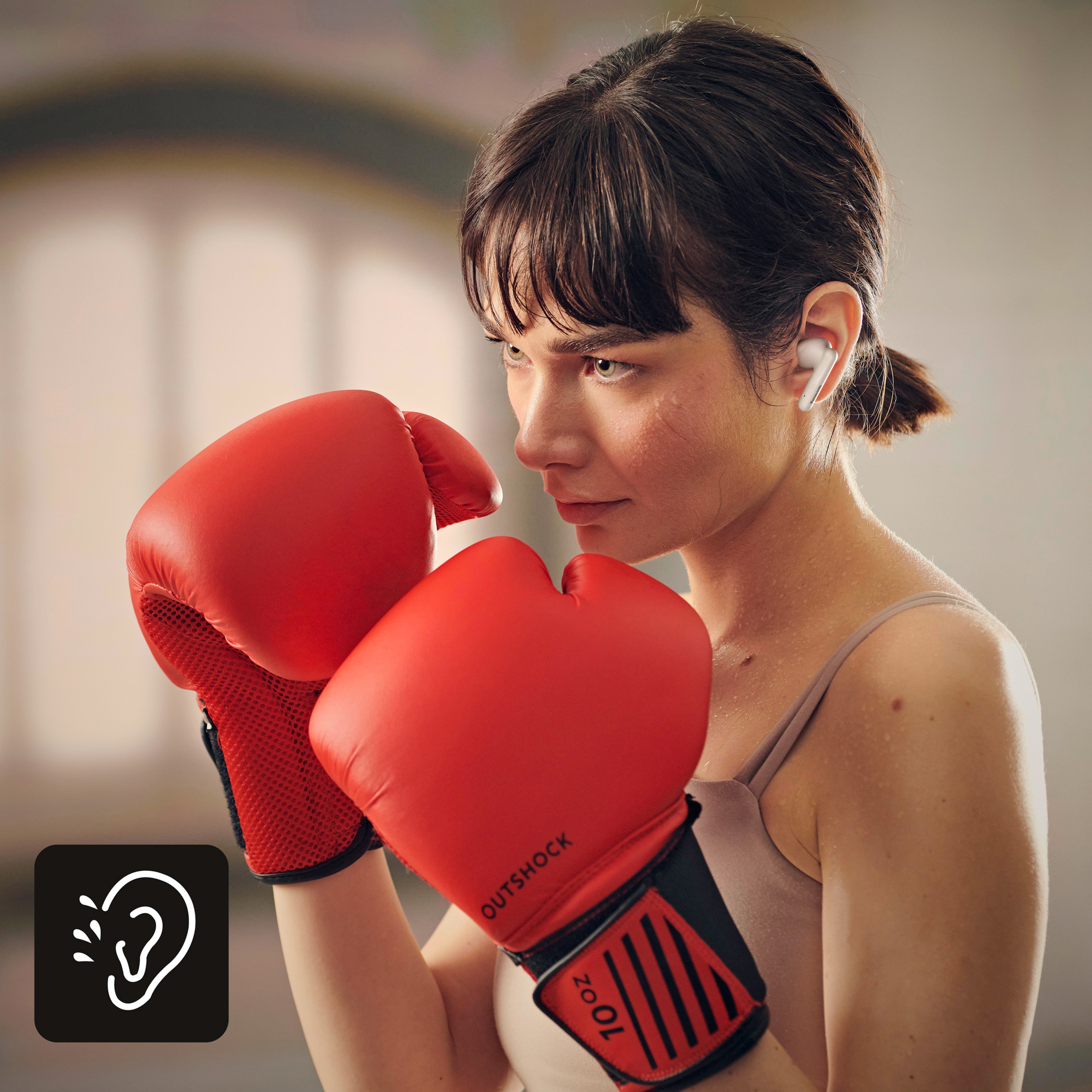 Eine Frau mit roten Boxhandschuhen und einem weißen Ohrhörer.