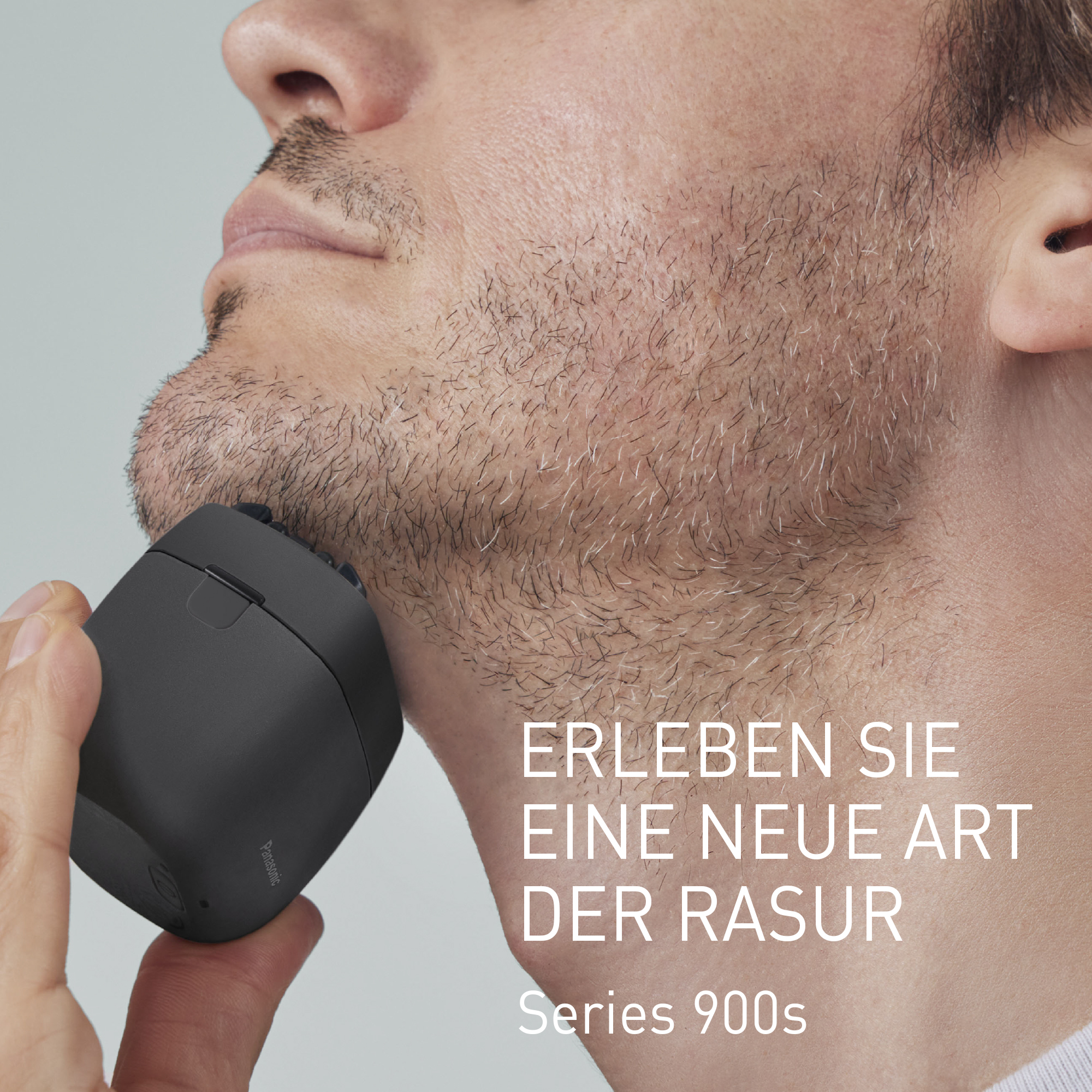 Mężczyzna goli twarz czarną maszynką Panasonic. Seria 900s.