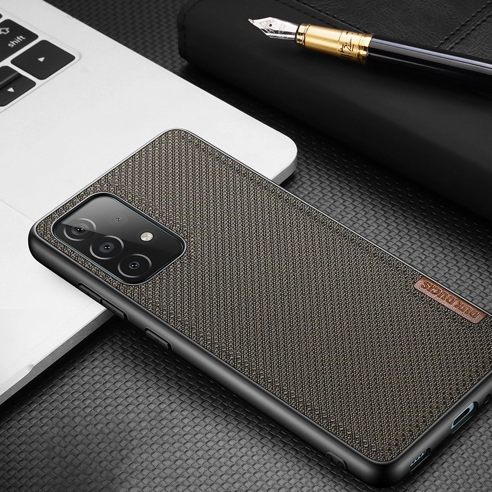 Uno smartphone nero con una custodia testurizzata grigio scuro e un'etichetta marrone giace su una tastiera bianca di laptop con una penna.