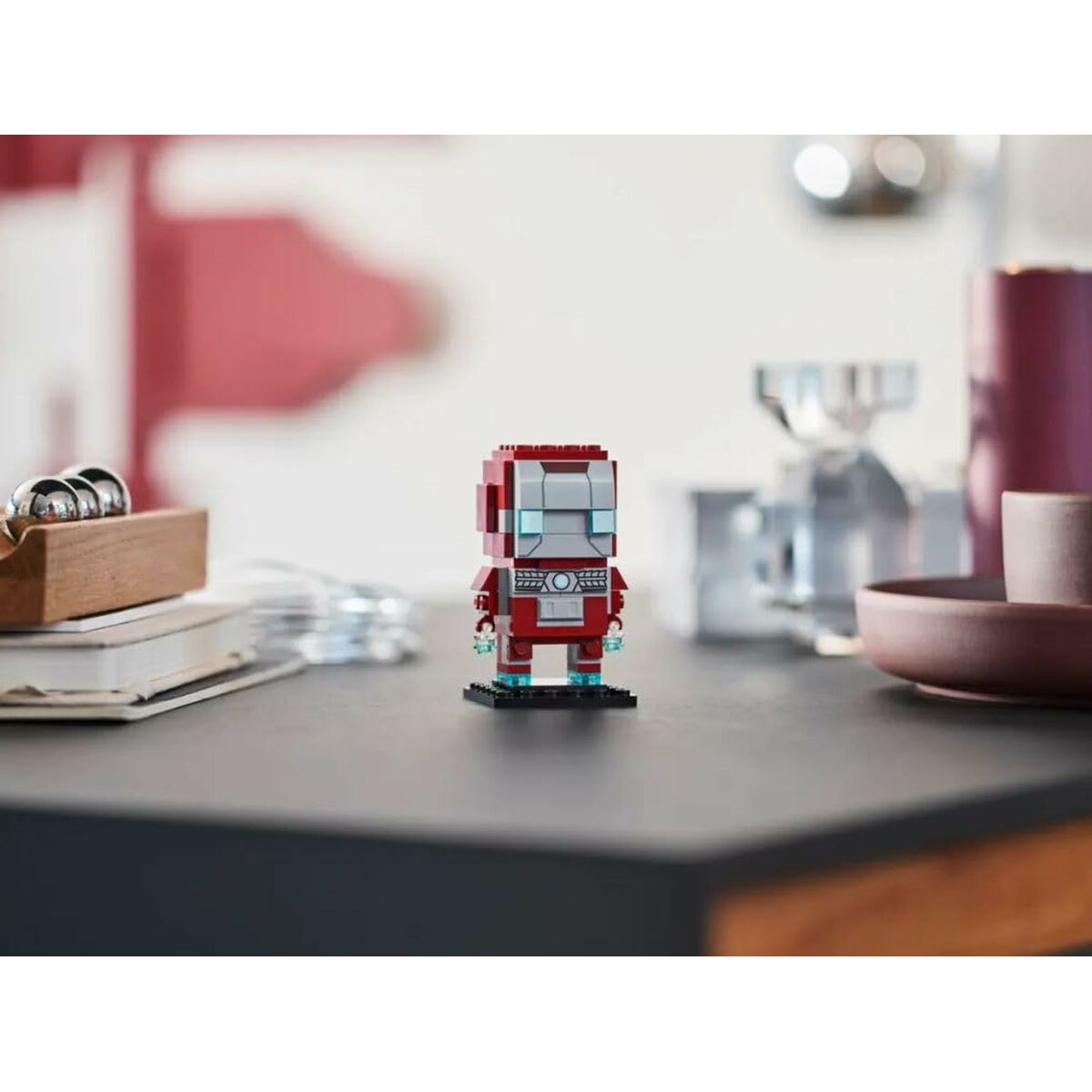 Küçük kırmızı ve gümüş Lego Iron Man figürü siyah bir tabanda duruyor.