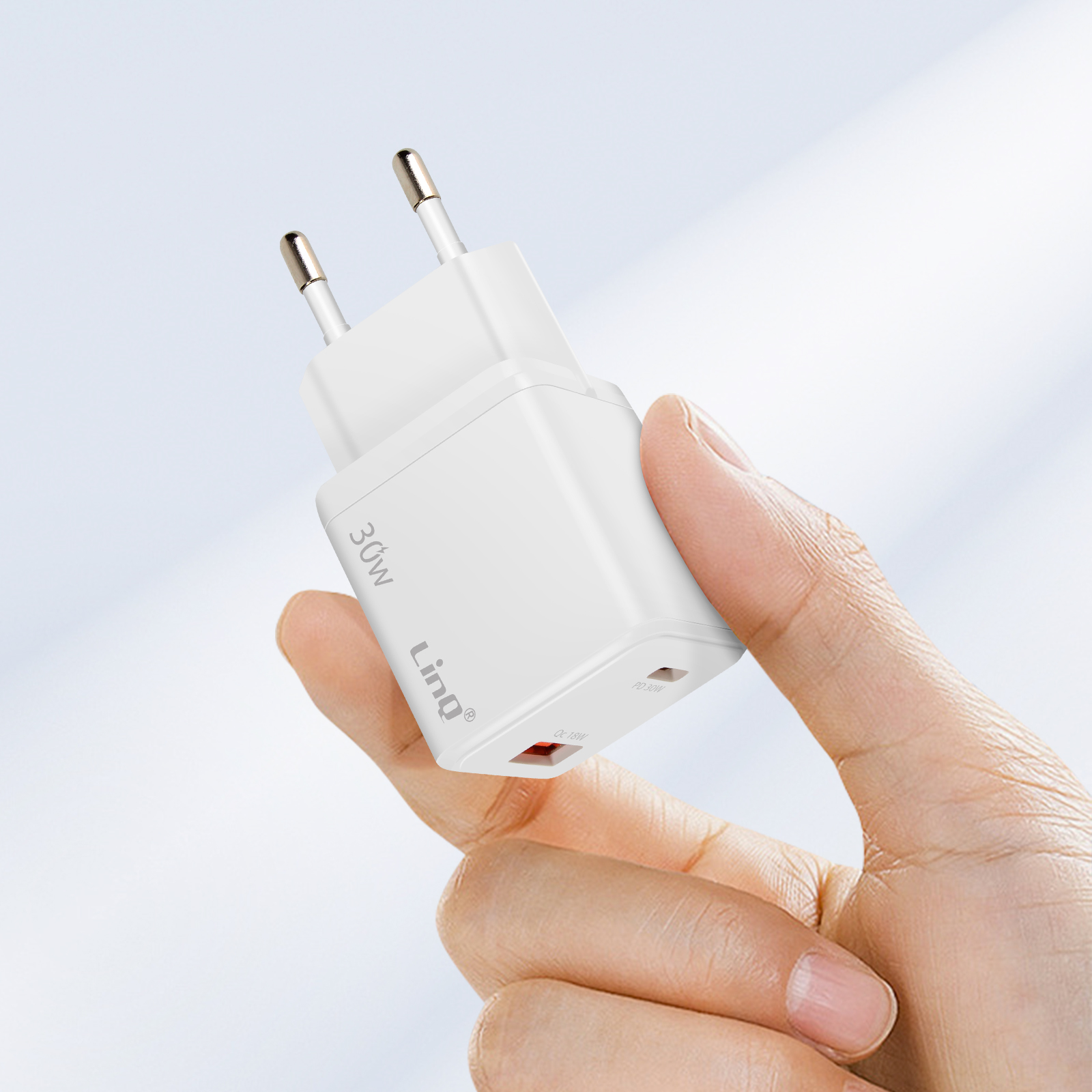 Un caricatore bianco da 30W con due porte è tenuto da una mano.