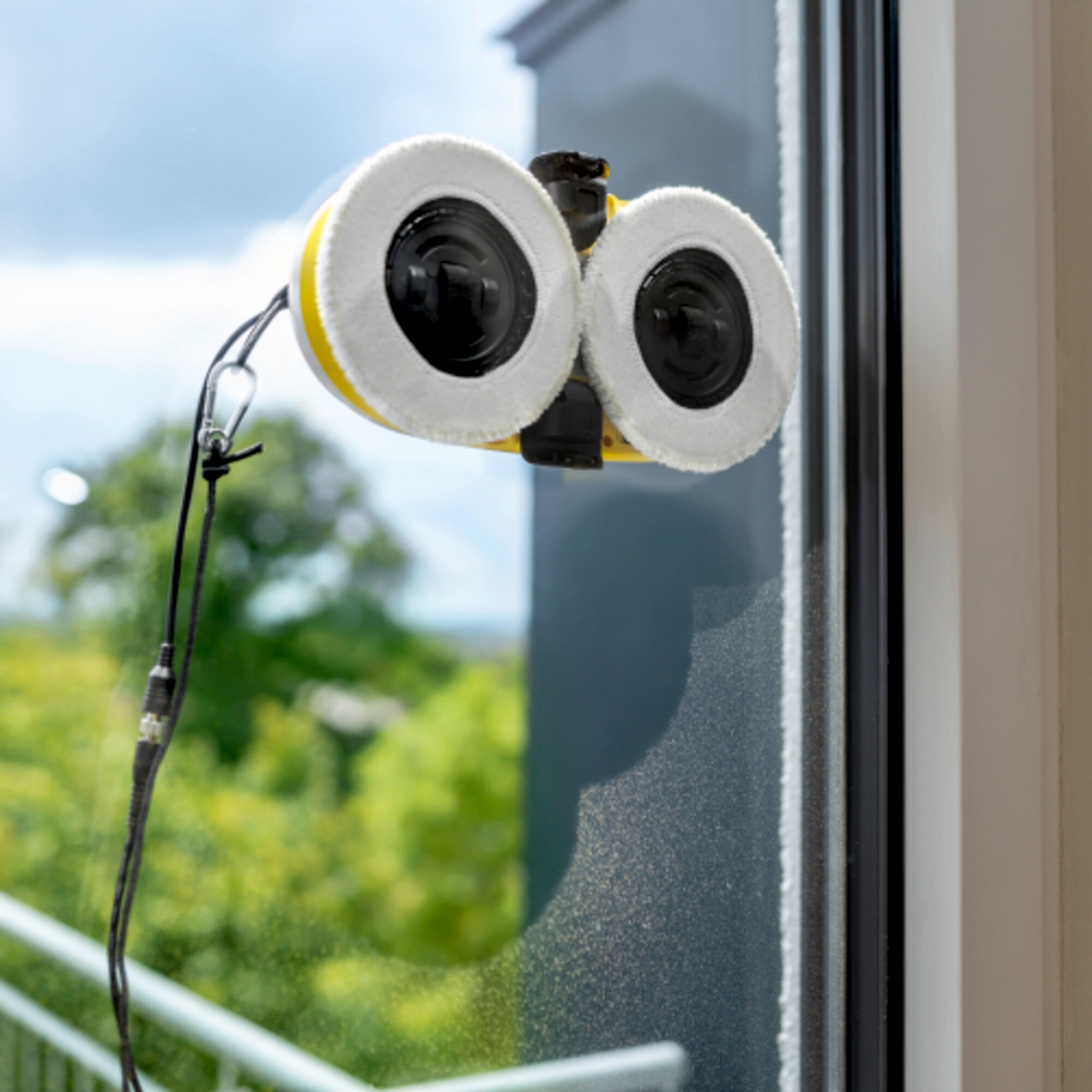 Ein Roboter-Fensterputzer mit zwei weißen Pads auf einem Fenster.