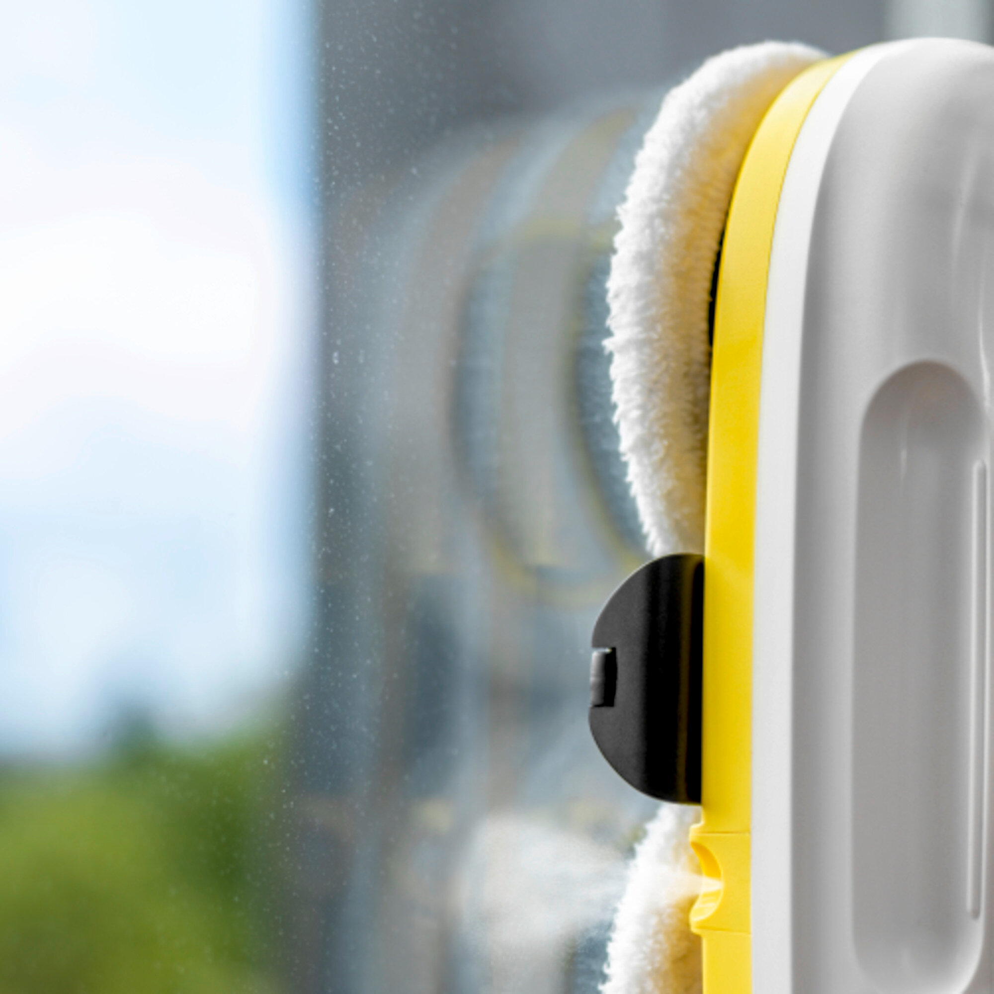 Ein gelber und weißer Fensterreinigungsroboter reinigt eine Fensterscheibe.