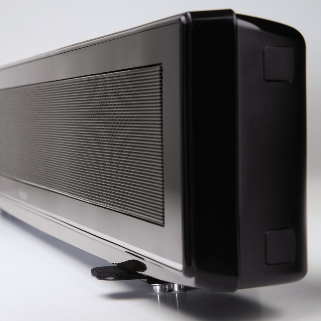 Czarny głośnik z drobnymi paskami z przodu i srebrnymi nóżkami.