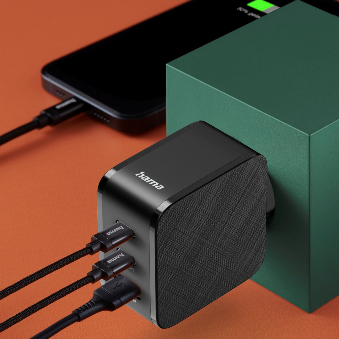 Czarna ładowarka Hama z trzema podłączonymi kablami, podłączona do telefonu.