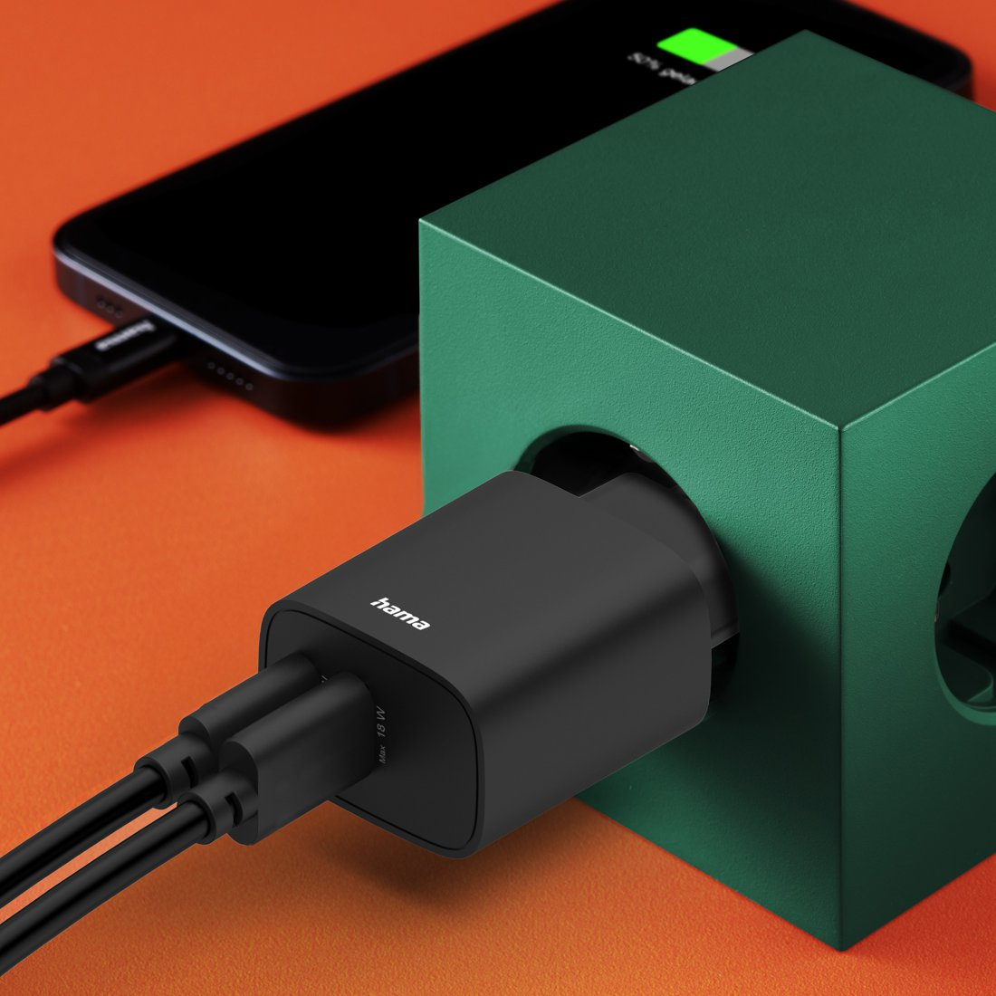 Czarna ładowarka ładuje telefon. Zielony uchwyt kostka.