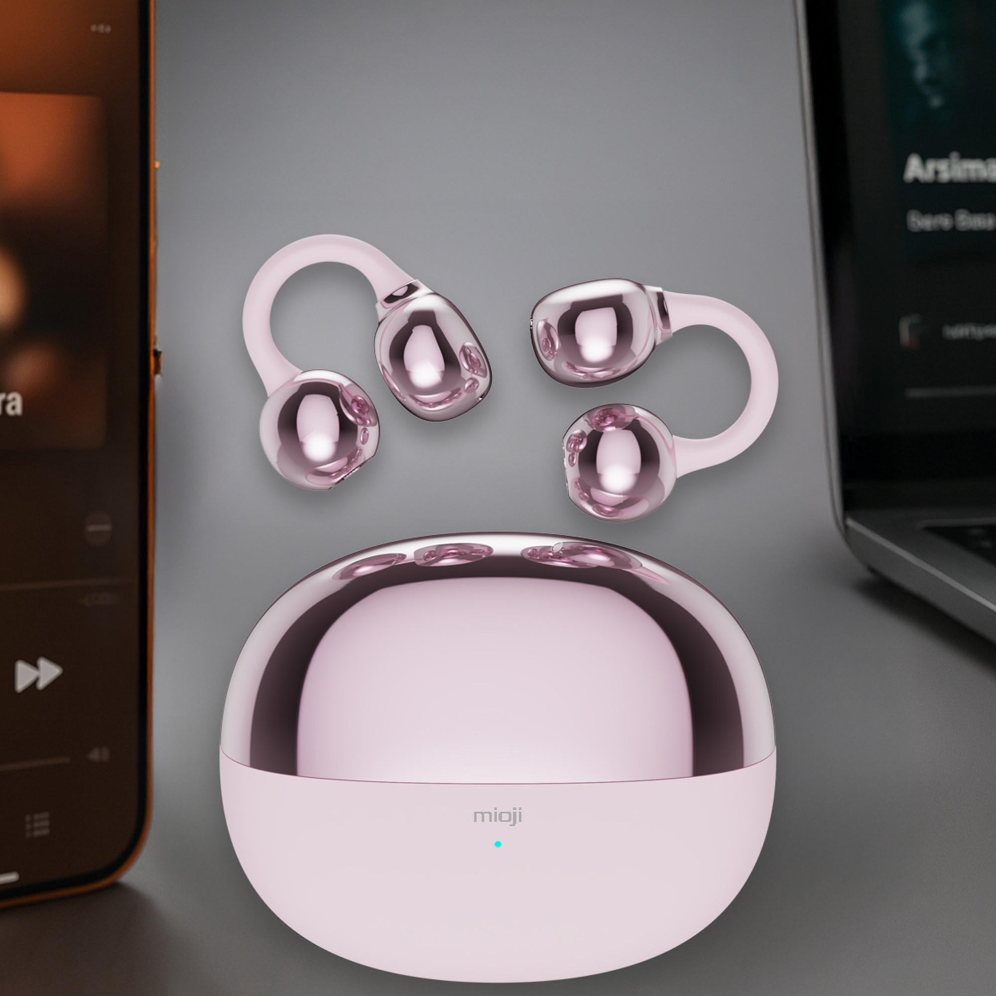 Parlak metal başlıklı pembe masaj cihazı, telefon ve dizüstü bilgisayarın yanında.