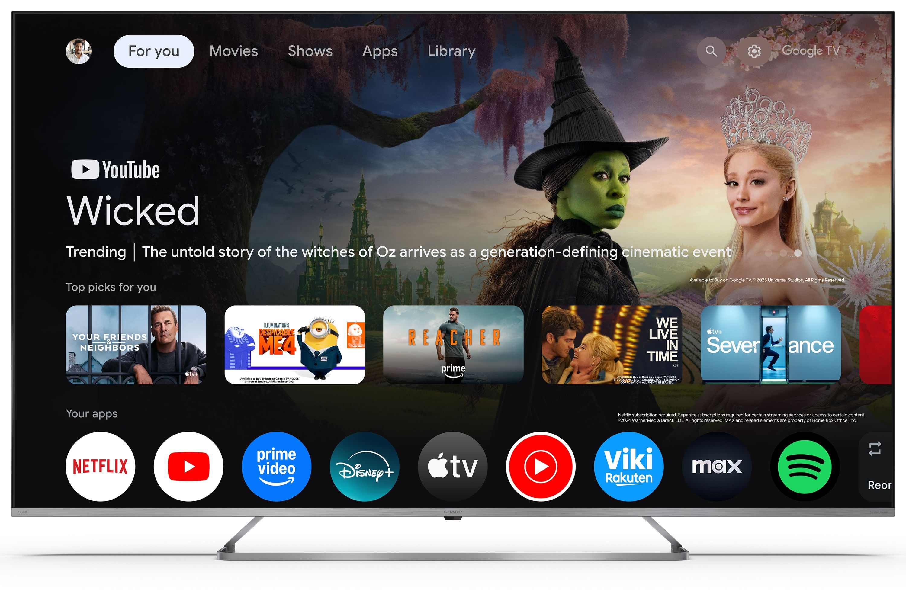 Uno schermo TV mostra l'interfaccia Google TV con film e app. In primo piano una strega verde e una principessa.