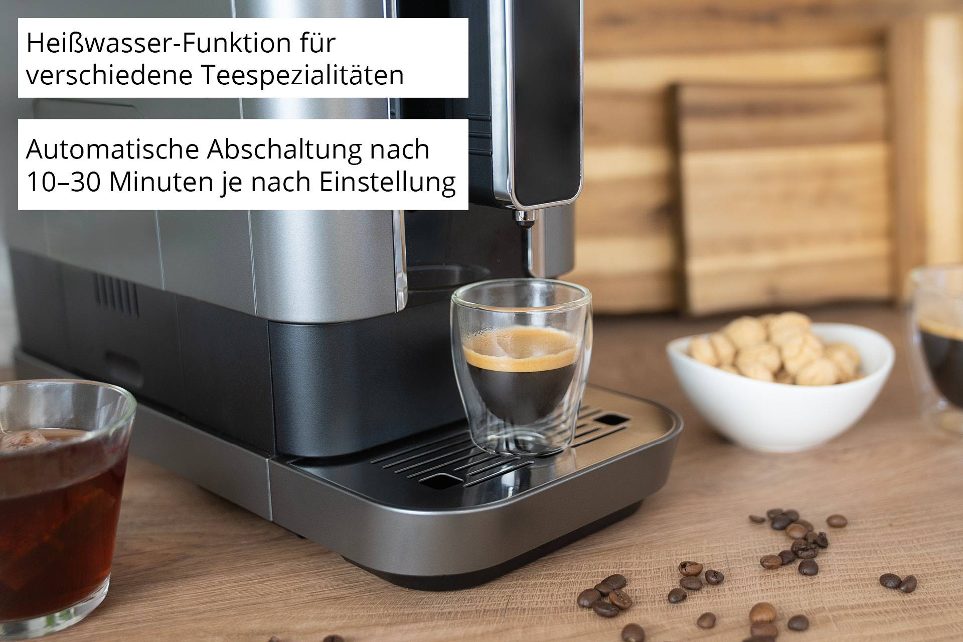 Kaffeemaschine mit Espresso, Tee und Keksen auf einem Holztisch.