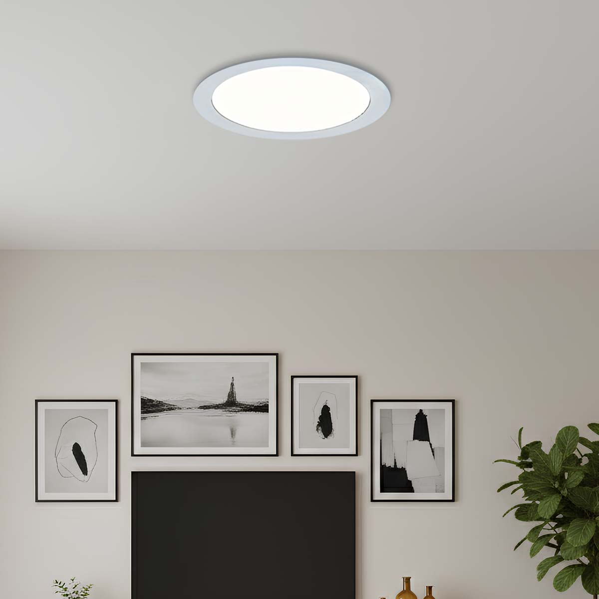 Una lámpara redonda de techo ilumina una habitación con cuatro cuadros.