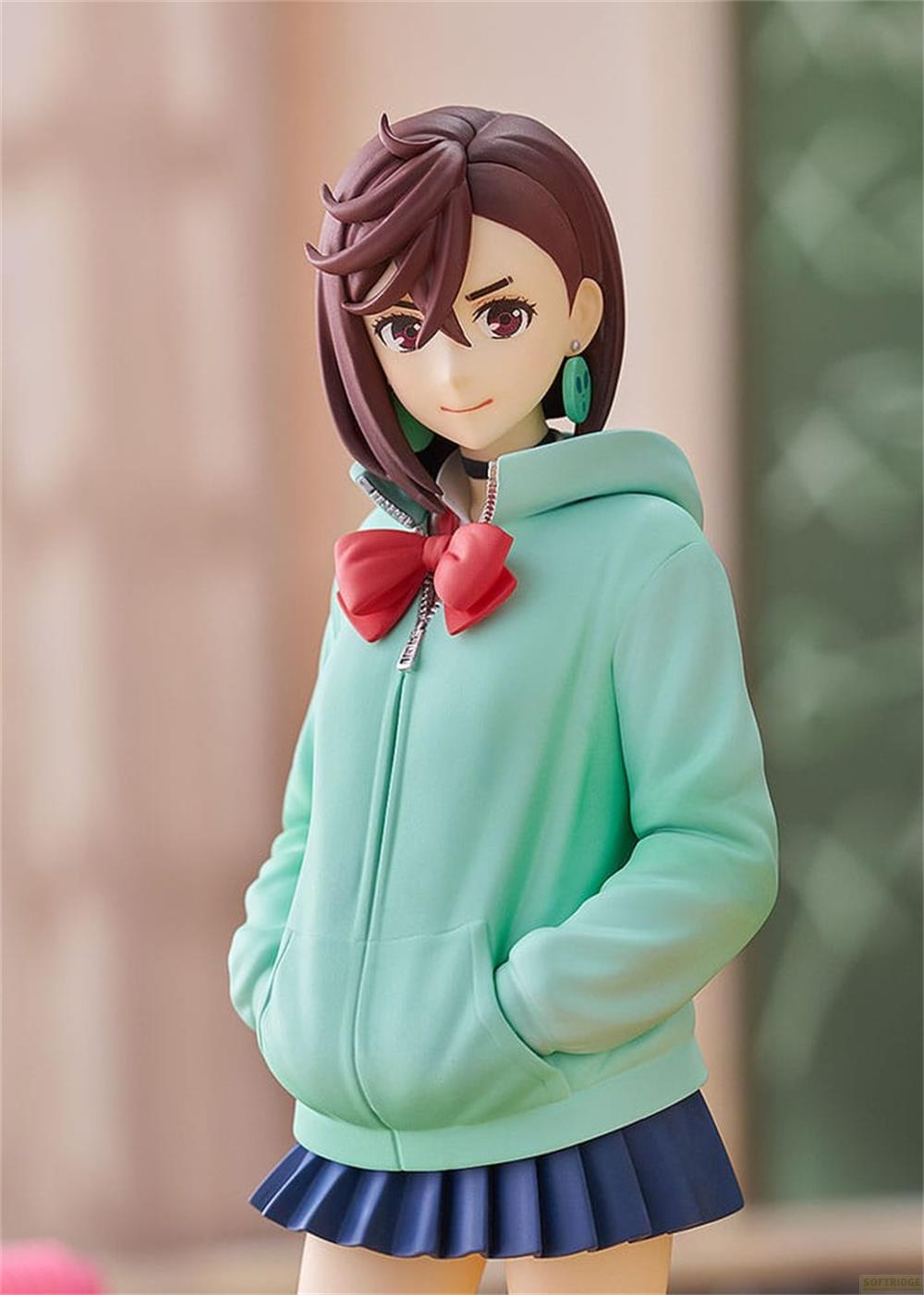 Figura de anime con pelo castaño, sudadera verde menta, lazo rojo, falda plisada azul.