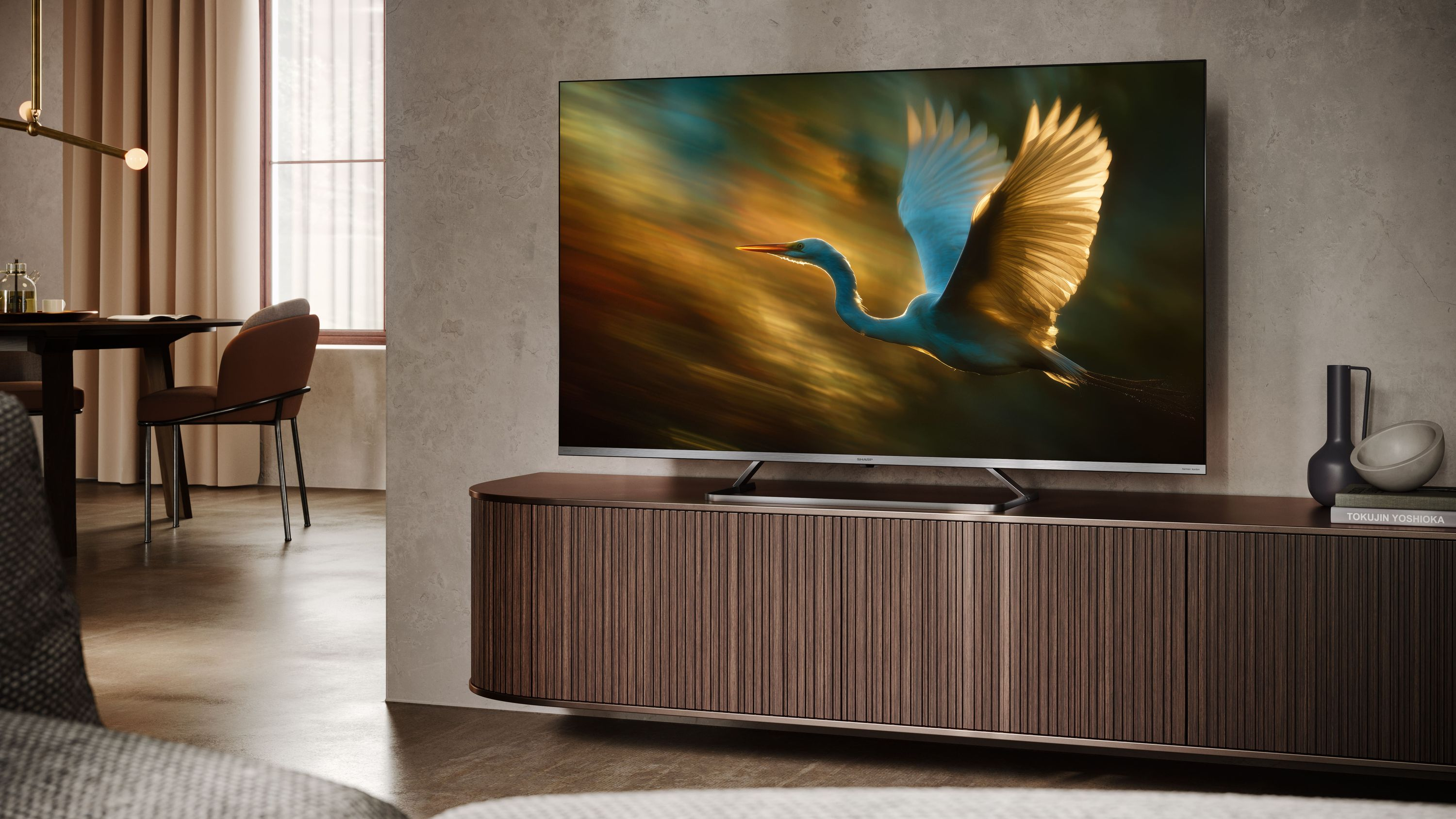 Una garzetta vola in un cielo dorato su uno schermo TV moderno.
