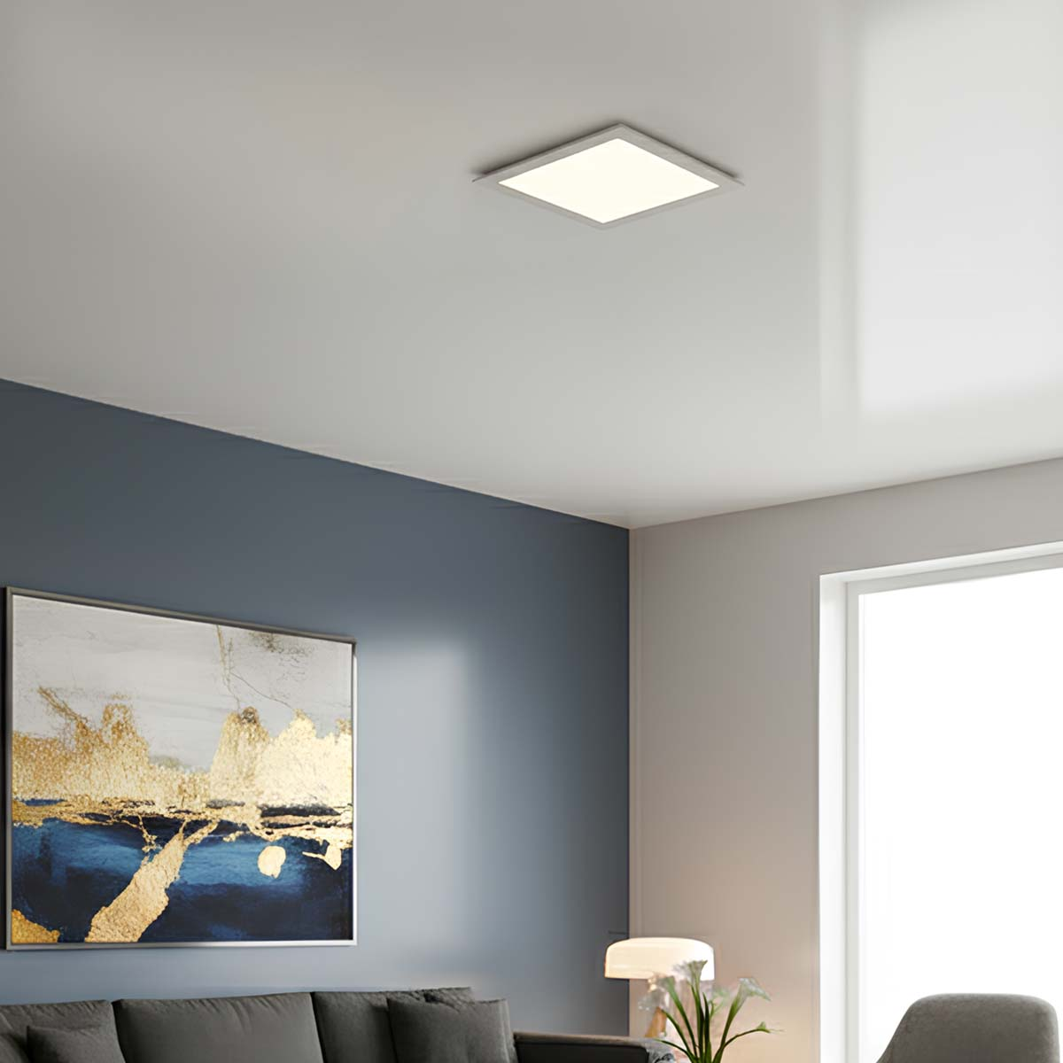 Una habitación moderna con luz de techo, cuadro y sofá.