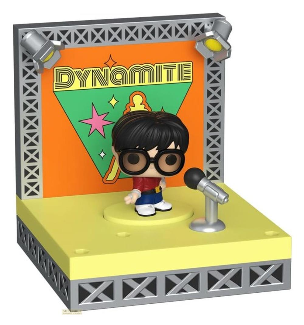 Eine Figur mit Brille steht auf einer Bühne vor dem Wort DYNAMITE.