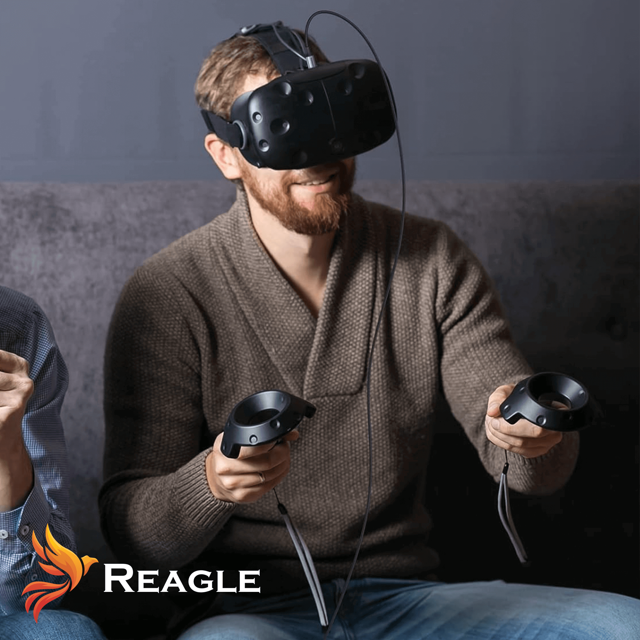 Mężczyzna w goglach VR i z kontrolerami siedzi na kanapie.