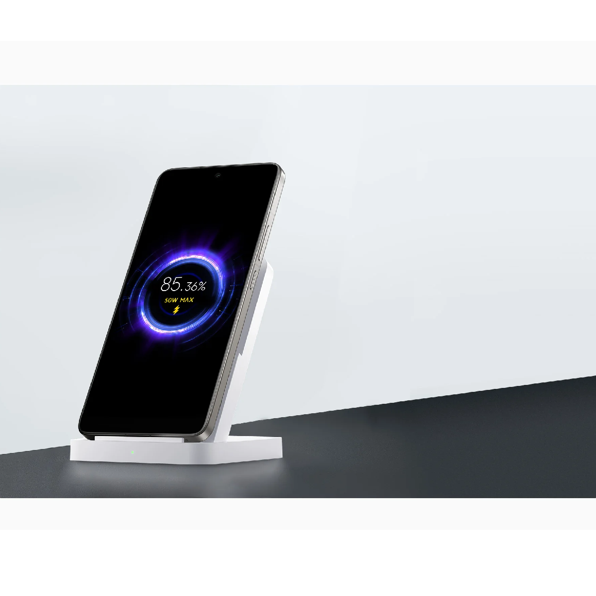 Smartfon ładuje się na białej podstawce. Ekran pokazuje 85,36%.