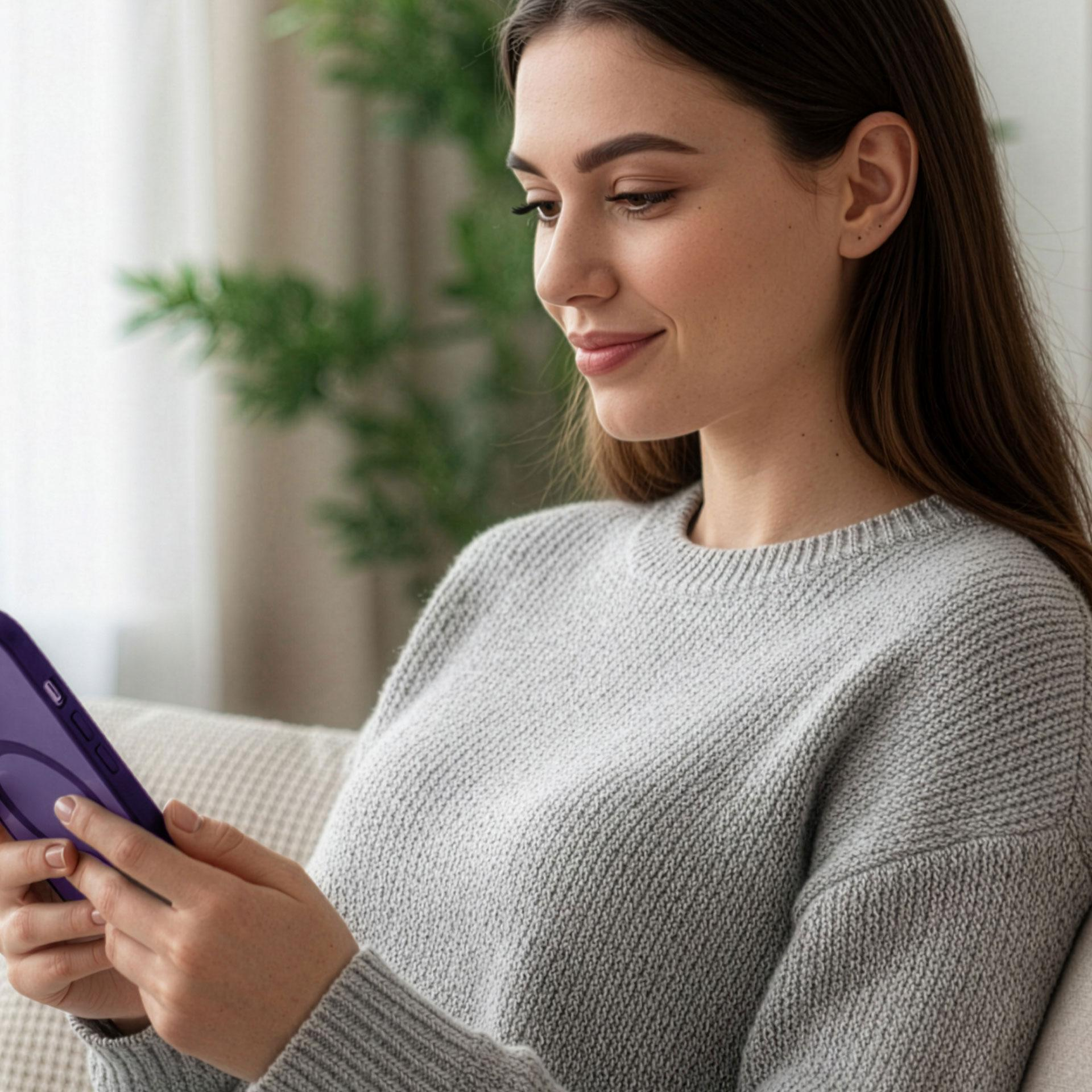 Kobieta z brązowymi włosami siedzi na kanapie i patrzy na fioletowy tablet.