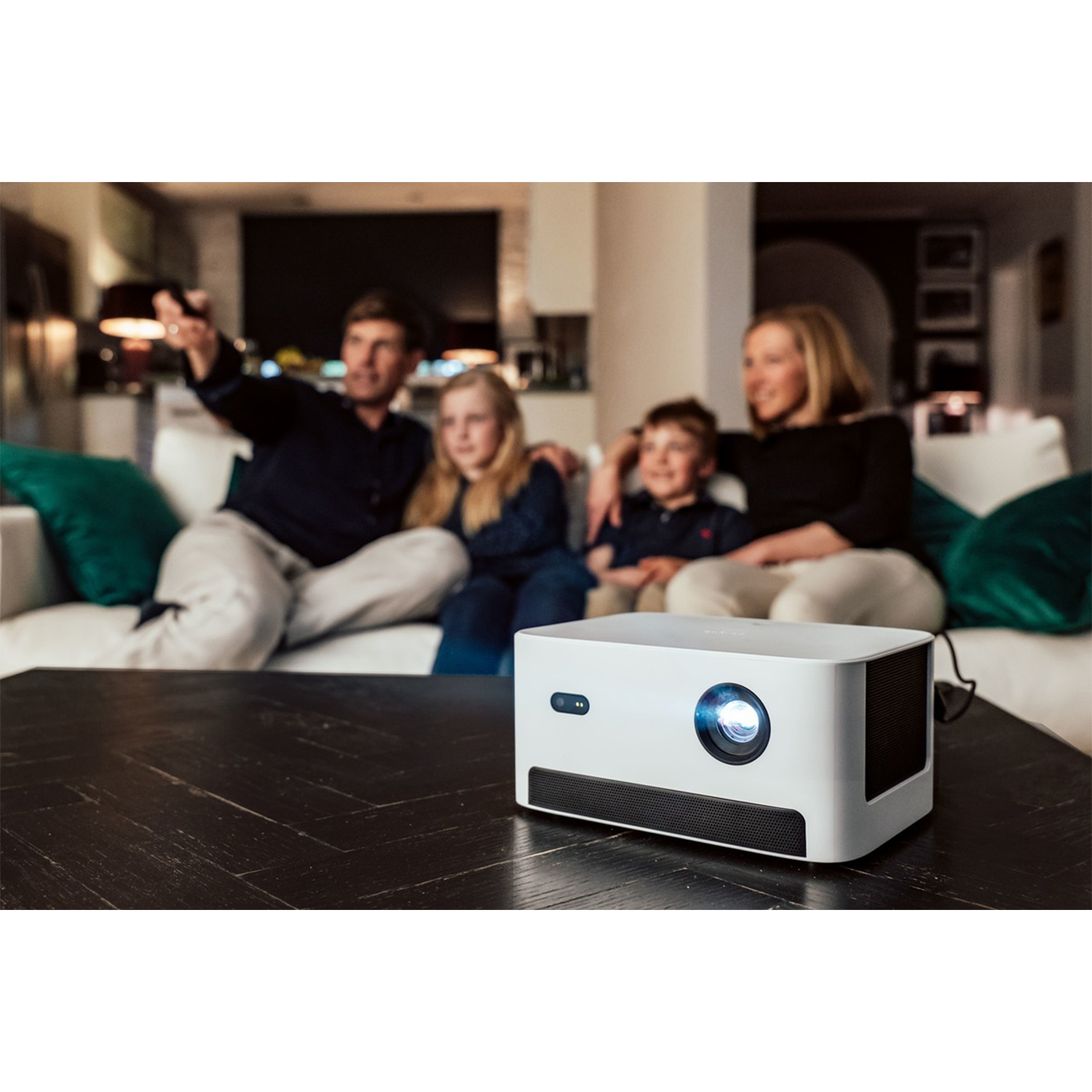 Rodzina ogląda TV na kanapie, projektor na stole.