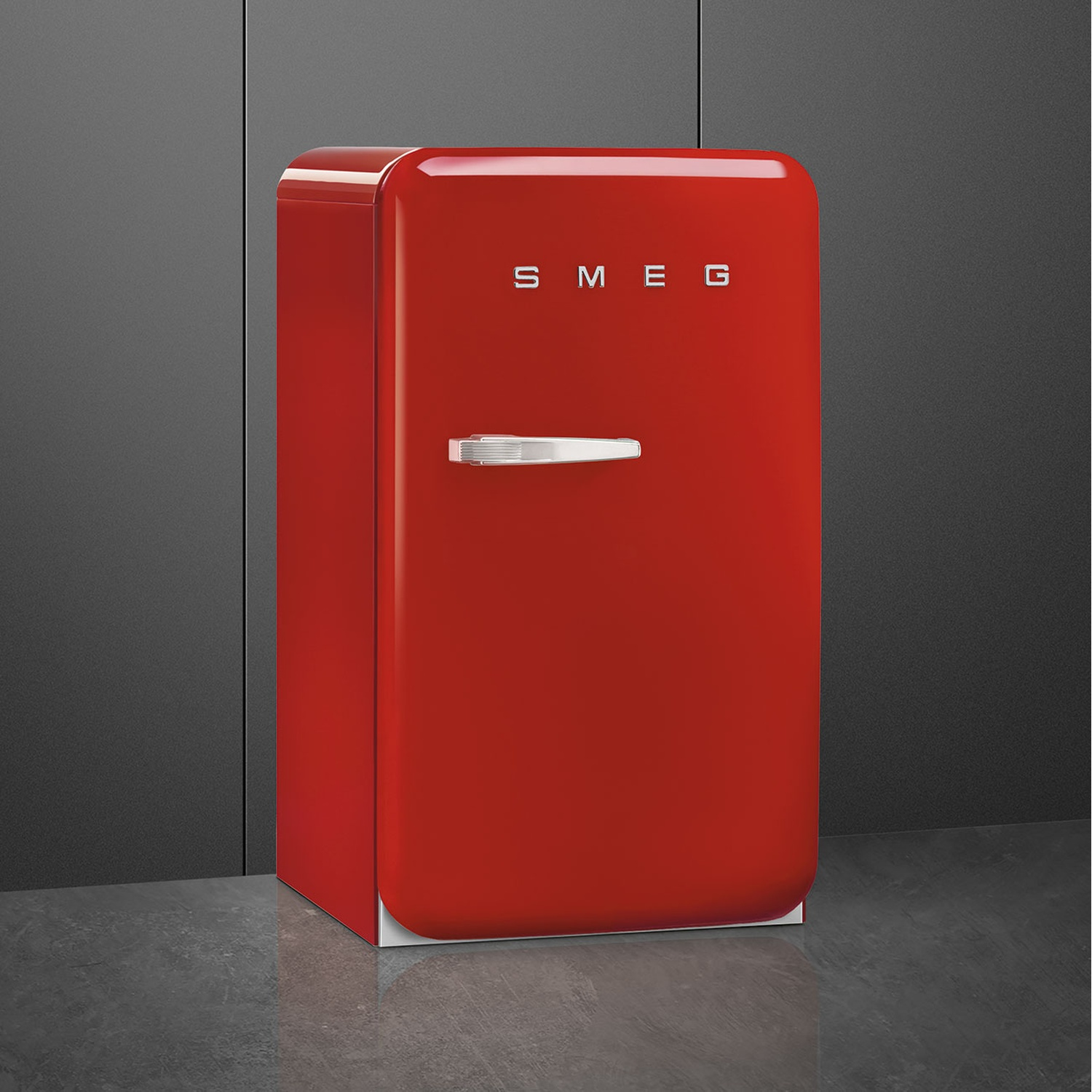 Un frigorífico SMEG rojo con asa plateada sobre suelo gris.