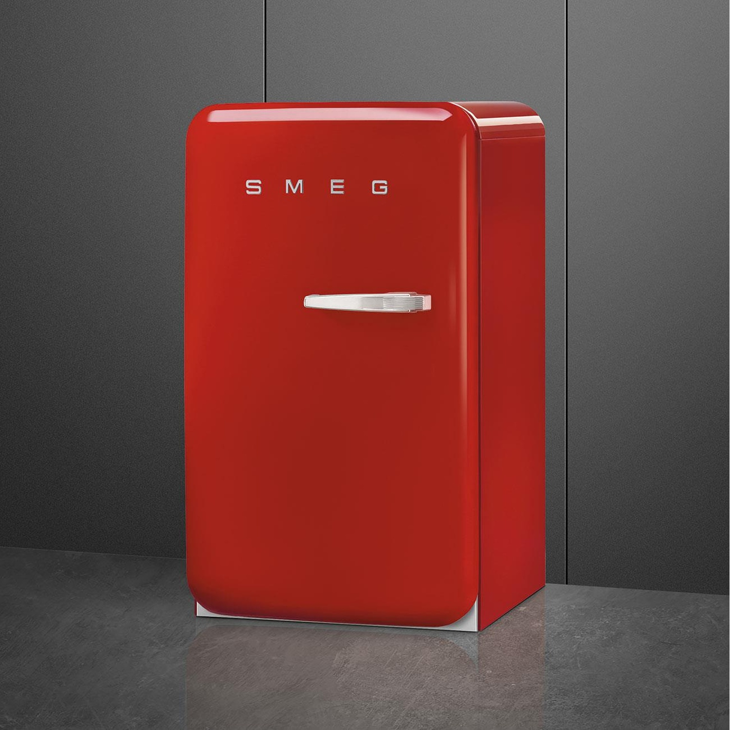 Un refrigerador SMEG rojo con asa plateada sobre suelo gris.