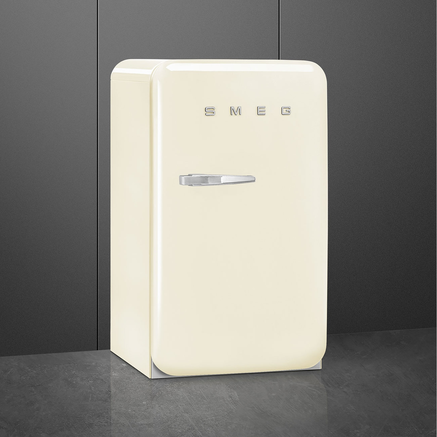 Un refrigerador Smeg color crema con asa plateada sobre un suelo oscuro.