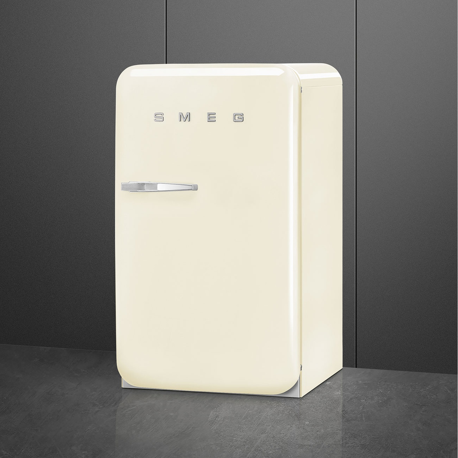 Un refrigerador Smeg color crema con asa plateada sobre suelo oscuro.