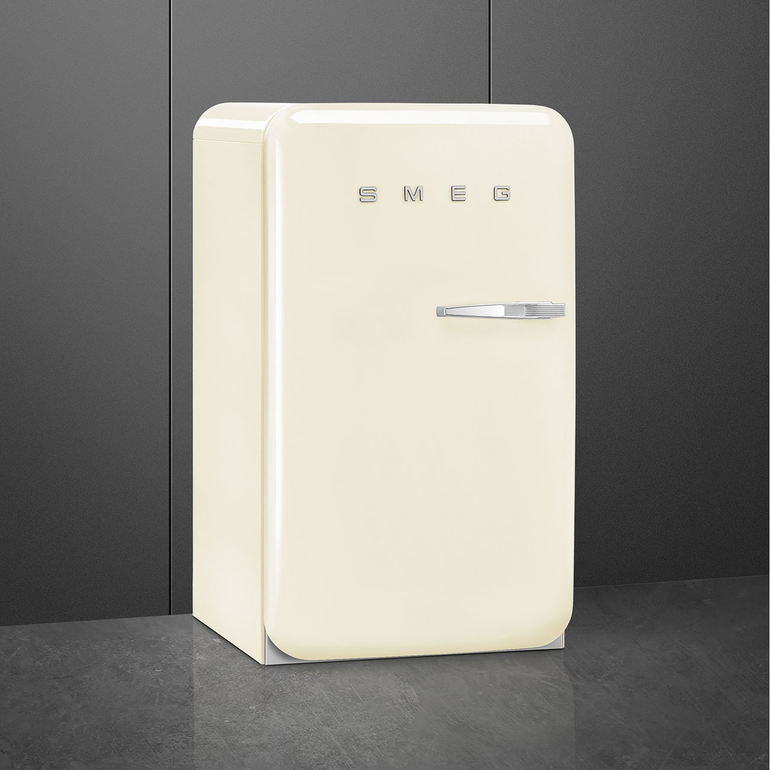 Un refrigerador Smeg color crema con asa plateada sobre suelo oscuro.