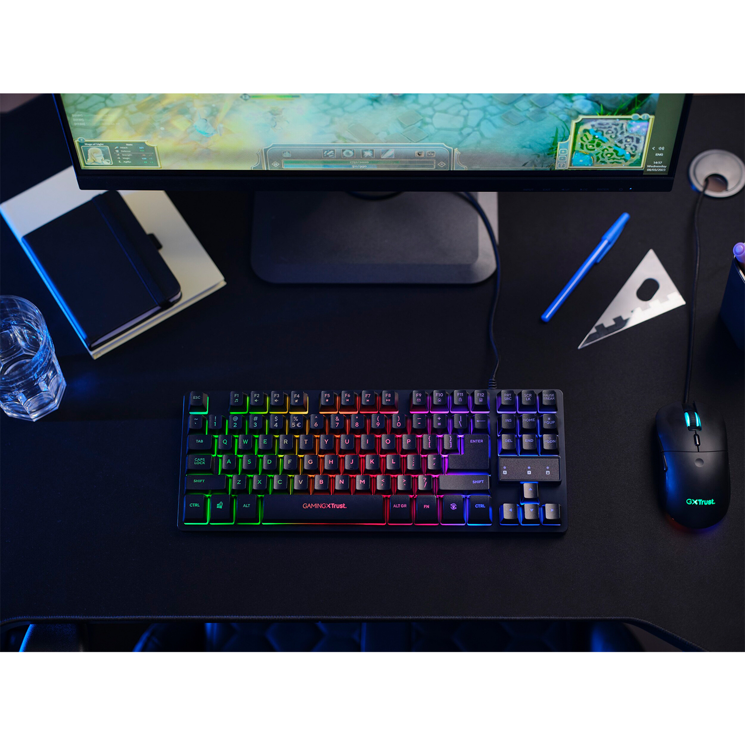 Tastiera e mouse gaming illuminati su un tappetino nero, con un monitor sullo sfondo.