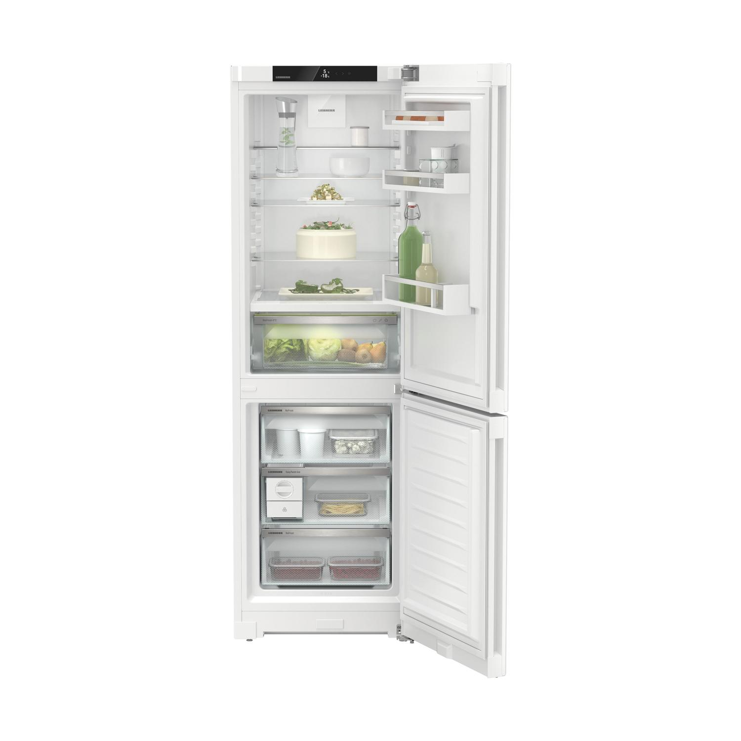Un refrigerador blanco con puerta abierta, lleno de comida. El congelador tiene recipientes.