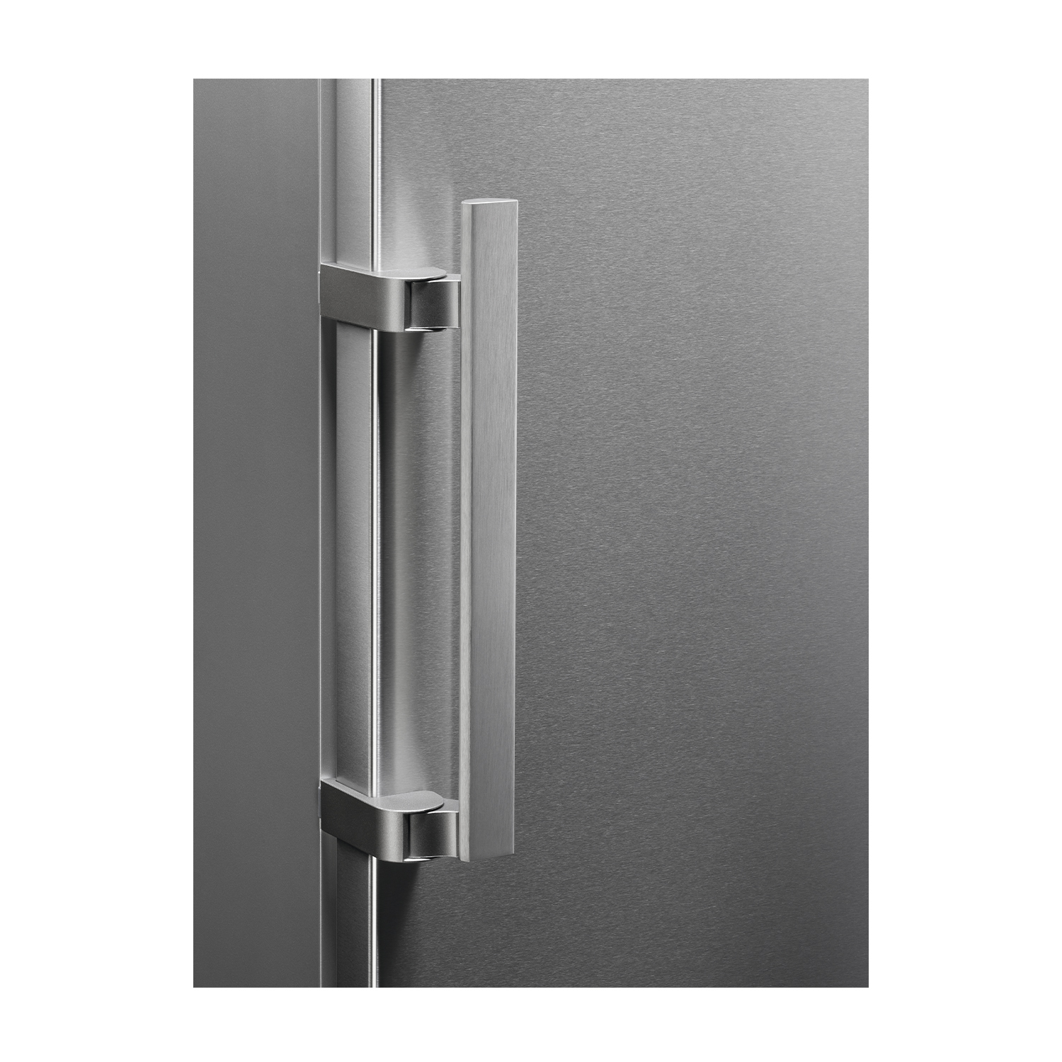 Un tirador plateado de frigorífico sobre una superficie de metal cepillado.