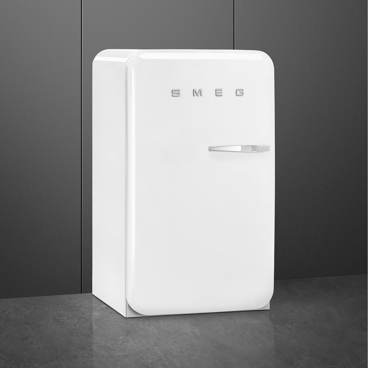 Un refrigerador SMEG blanco con tirador cromado sobre suelo oscuro.