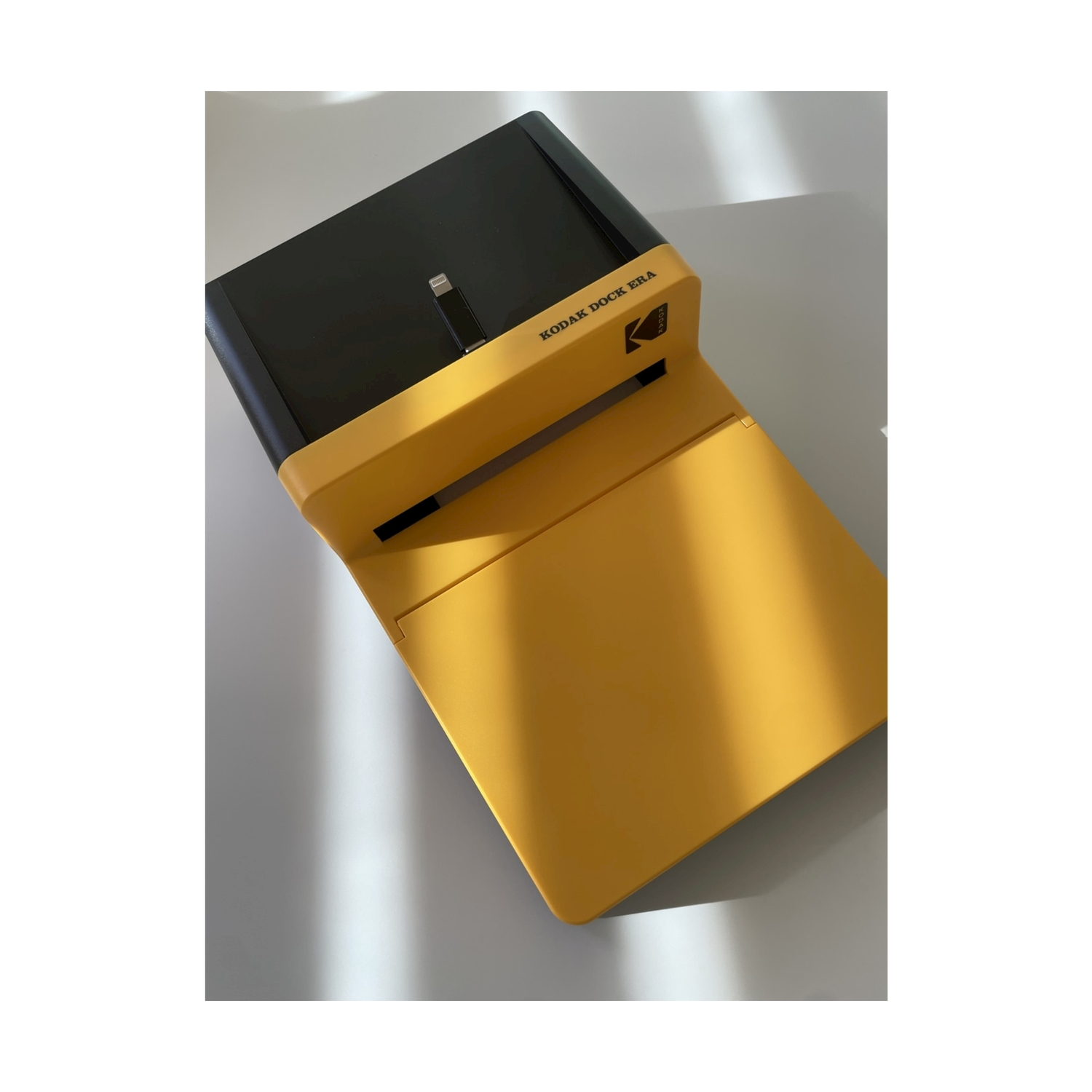 Una stampante Kodak Dock Era gialla con coperchio nero e connettore Lightning.