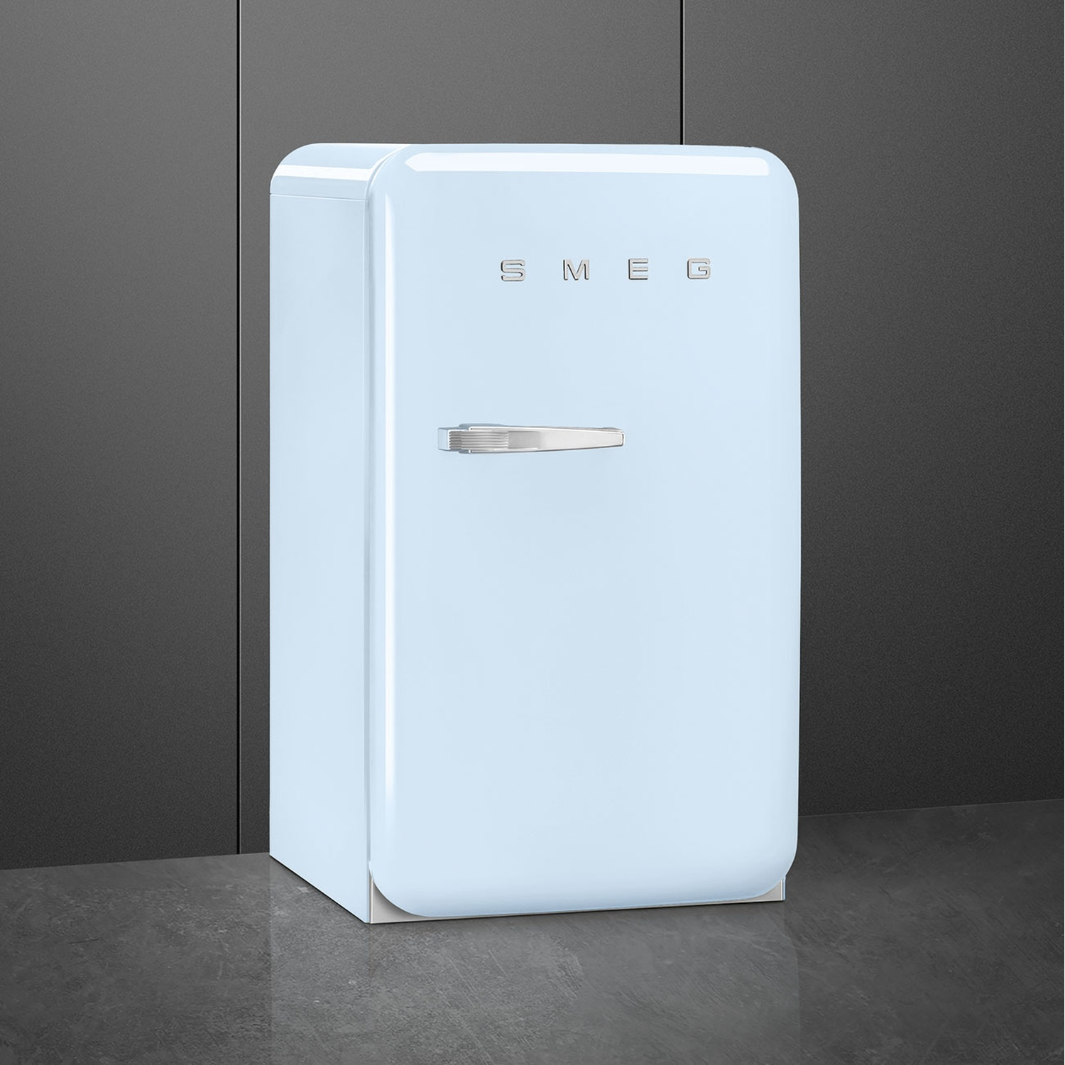 Un refrigerador Smeg azul claro con asa plateada sobre suelo oscuro.