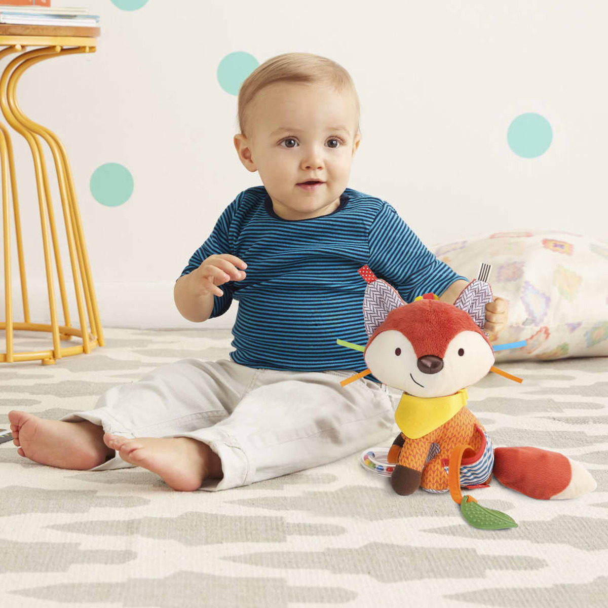 Ein Baby sitzt auf einem Teppich neben einem Fuchs-Stofftier.