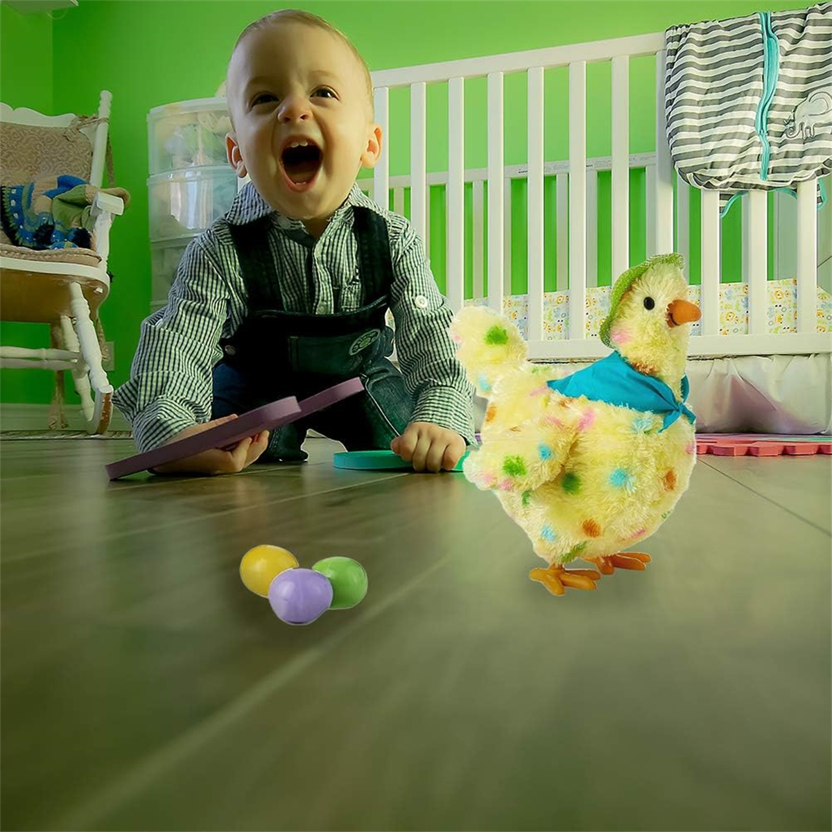 Ein Baby spielt auf dem Boden mit einem Spielzeughuhn und bunten Kugeln neben einem Kinderbett.