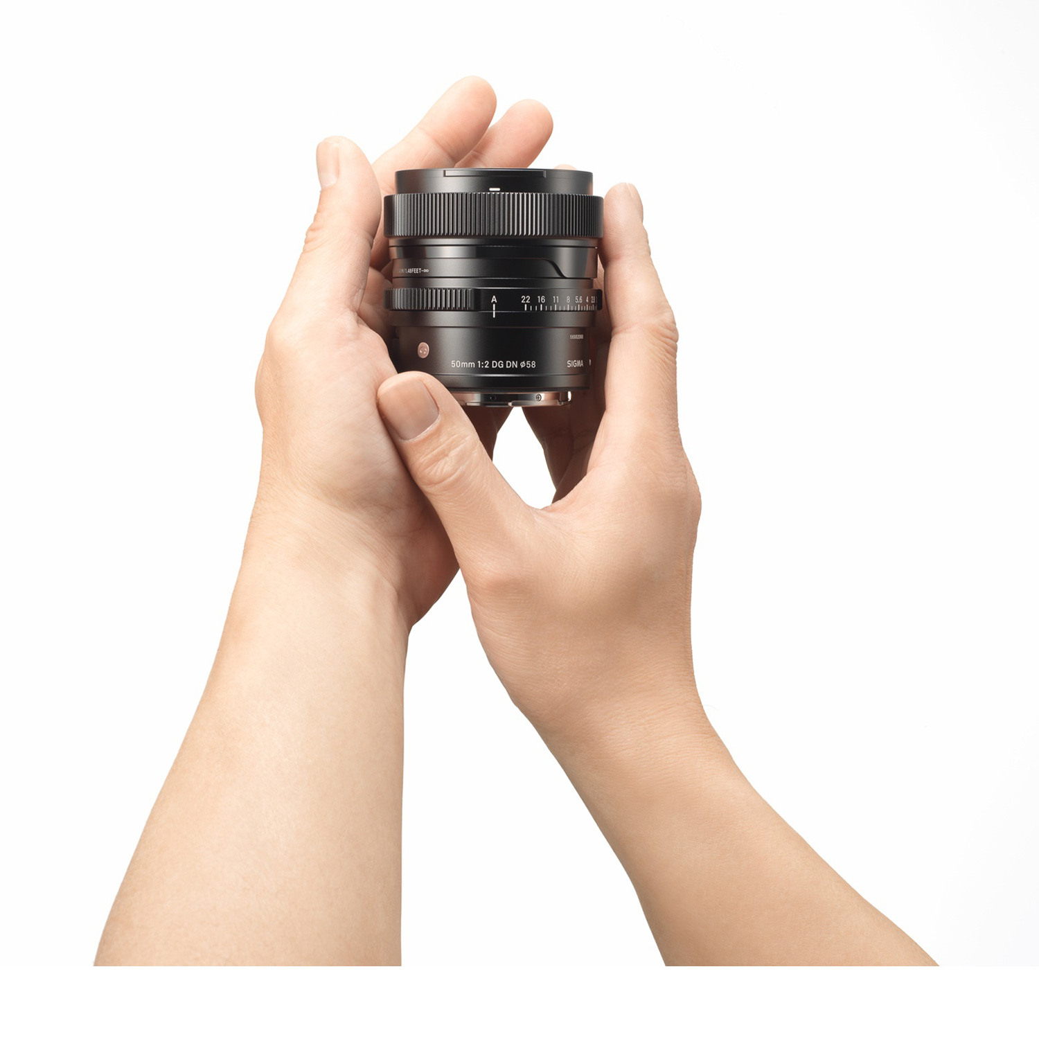 Dłonie trzymają czarny obiektyw aparatu z napisami.