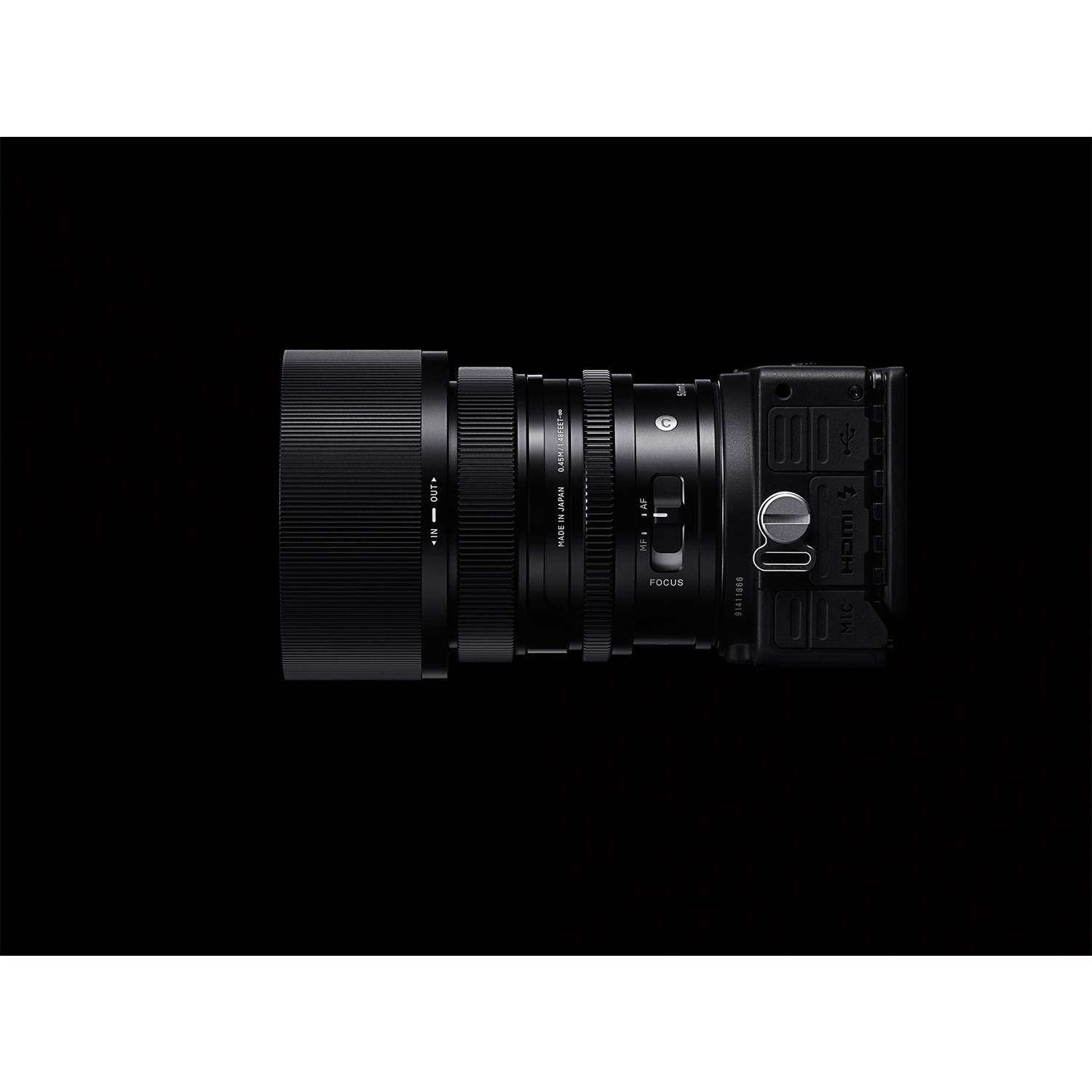 Czarny aparat z obiektywem, widziany z boku i od góry. Widoczny pierścień ostrości i porty.