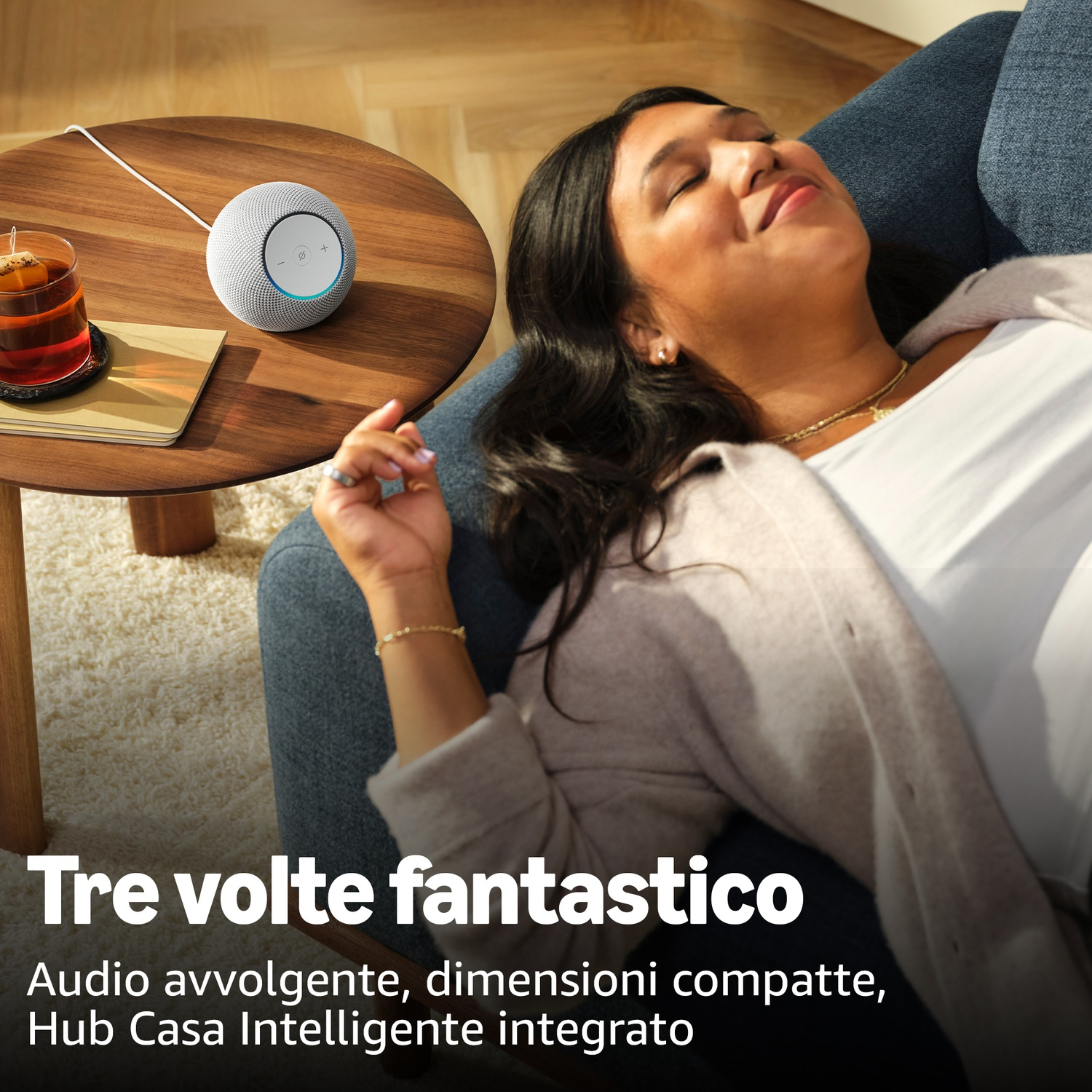 Eine Frau entspannt sich, ein Smart Speaker und Tee stehen auf einem Holztisch.