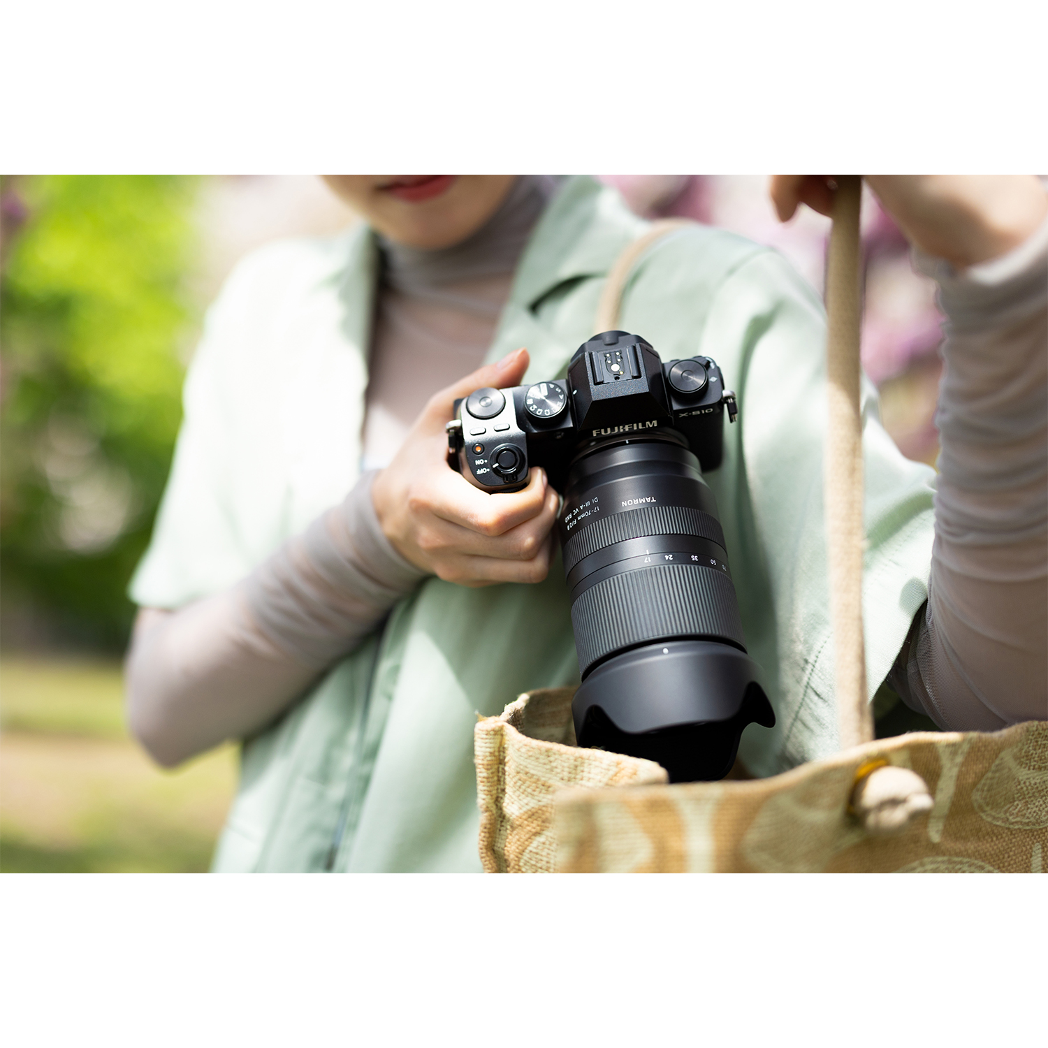 Osoba trzyma aparat Fujifilm z obiektywem Tamron w torbie.