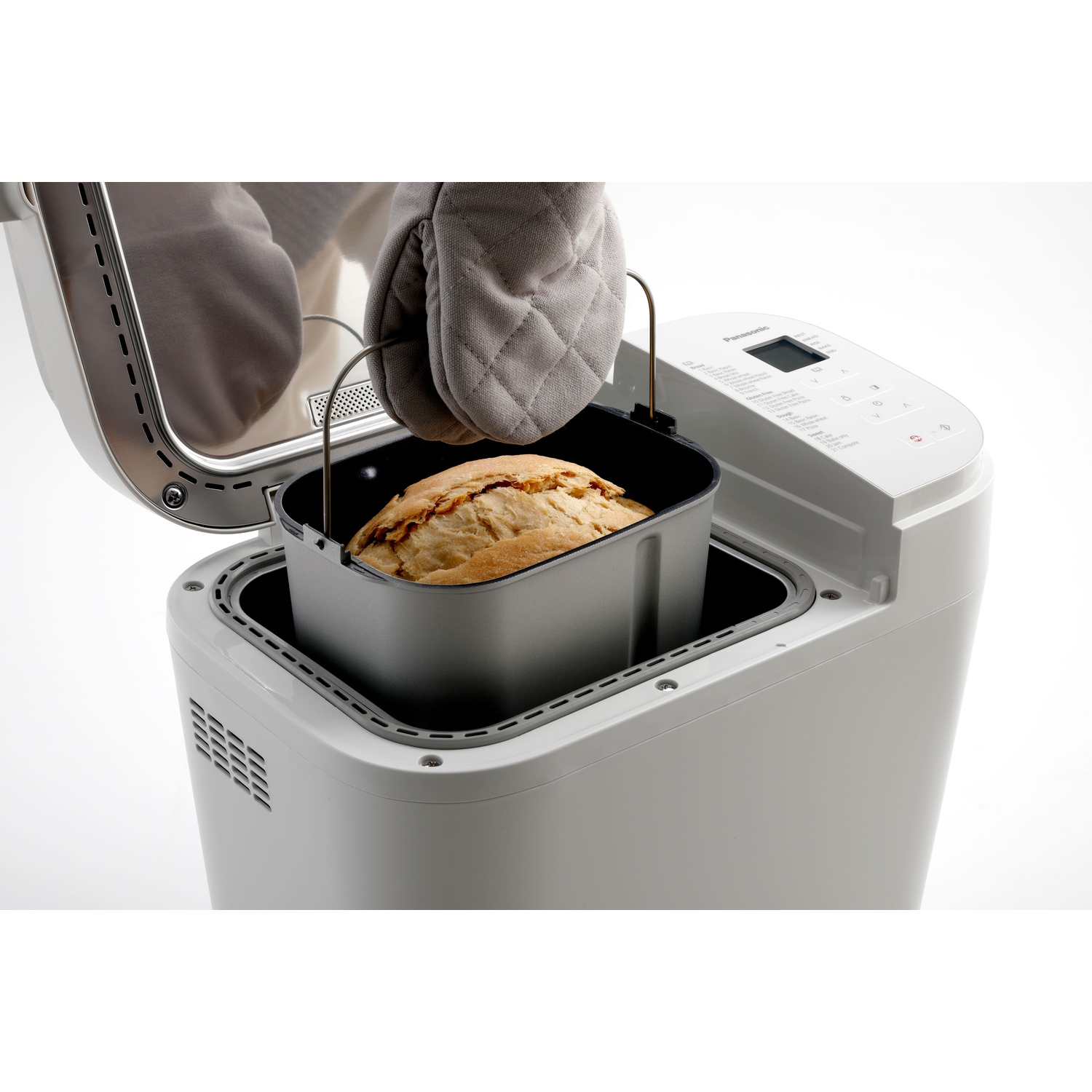 Grijze ovenwanten halen versgebakken brood uit een witte broodbakmachine.
