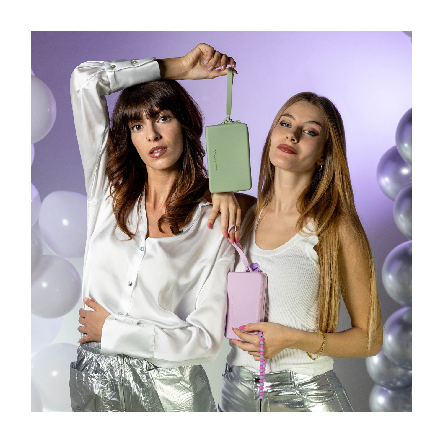 Dos mujeres posan con bolsos pasteles frente a globos.