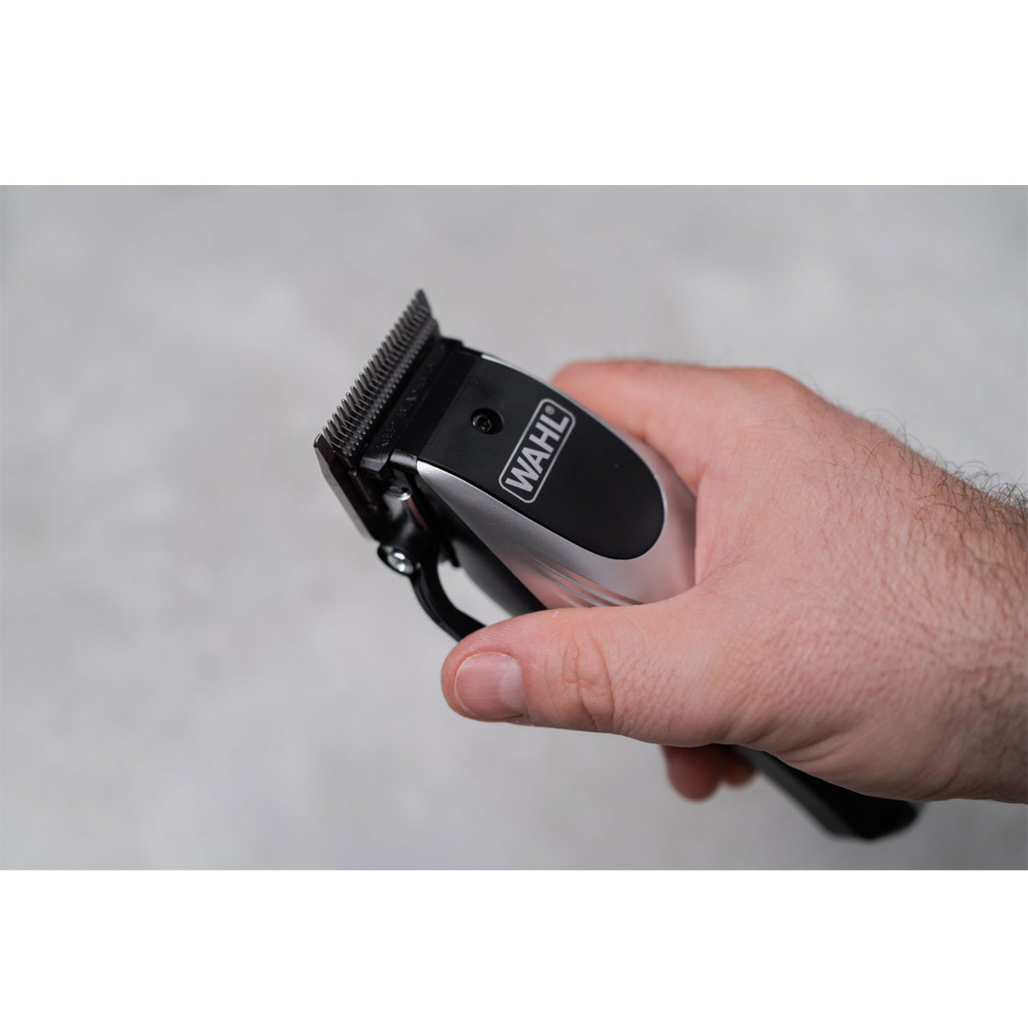 Dłoń trzyma srebrno-czarną maszynkę do strzyżenia Wahl.